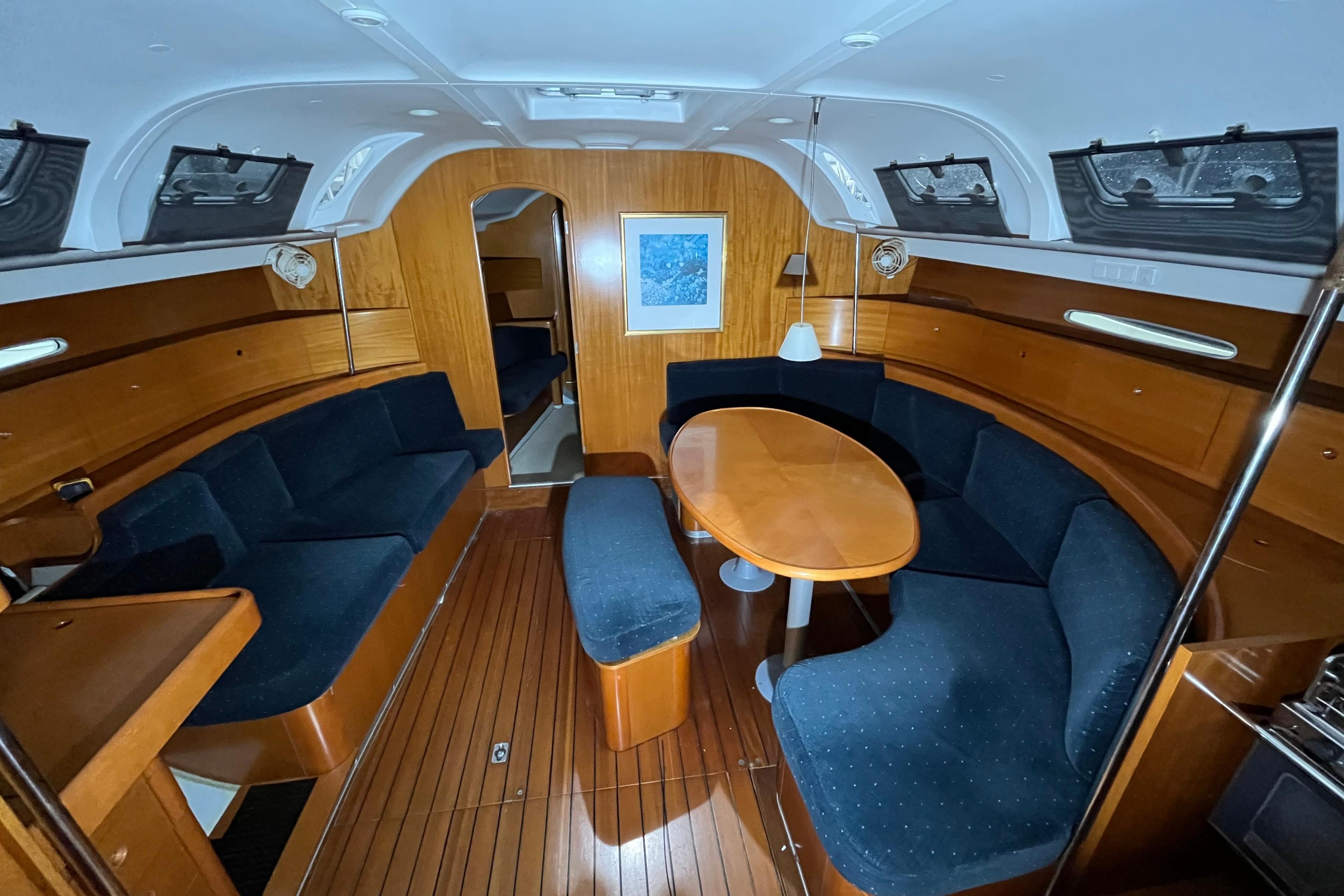 Interior of 1999 Beneteau First 42s7 yacht with wooden finish and blue seating.