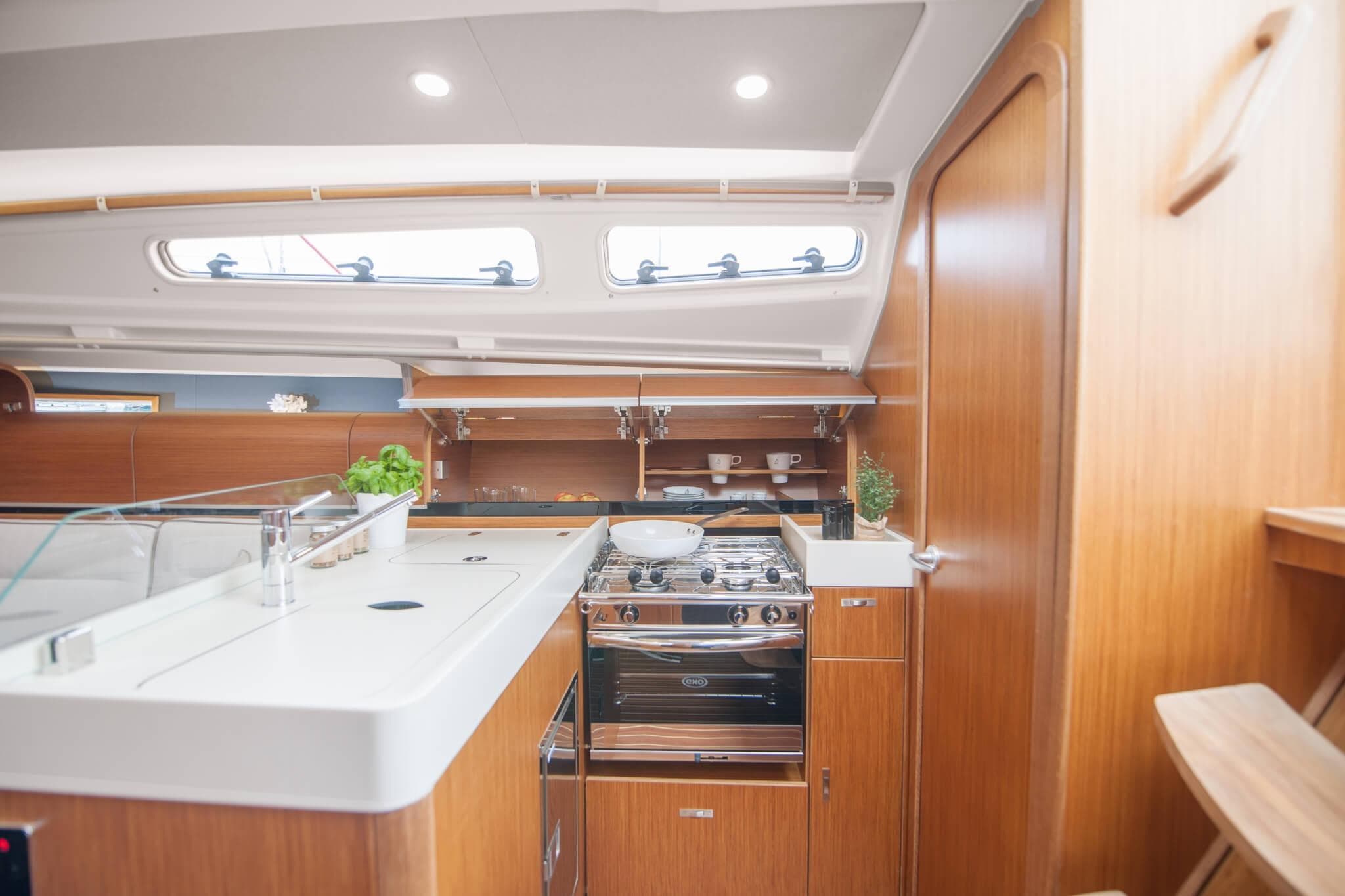 Modern kitchen interior of 2026 Dehler 34 yacht with wooden cabinetry and stainless steel appliances.