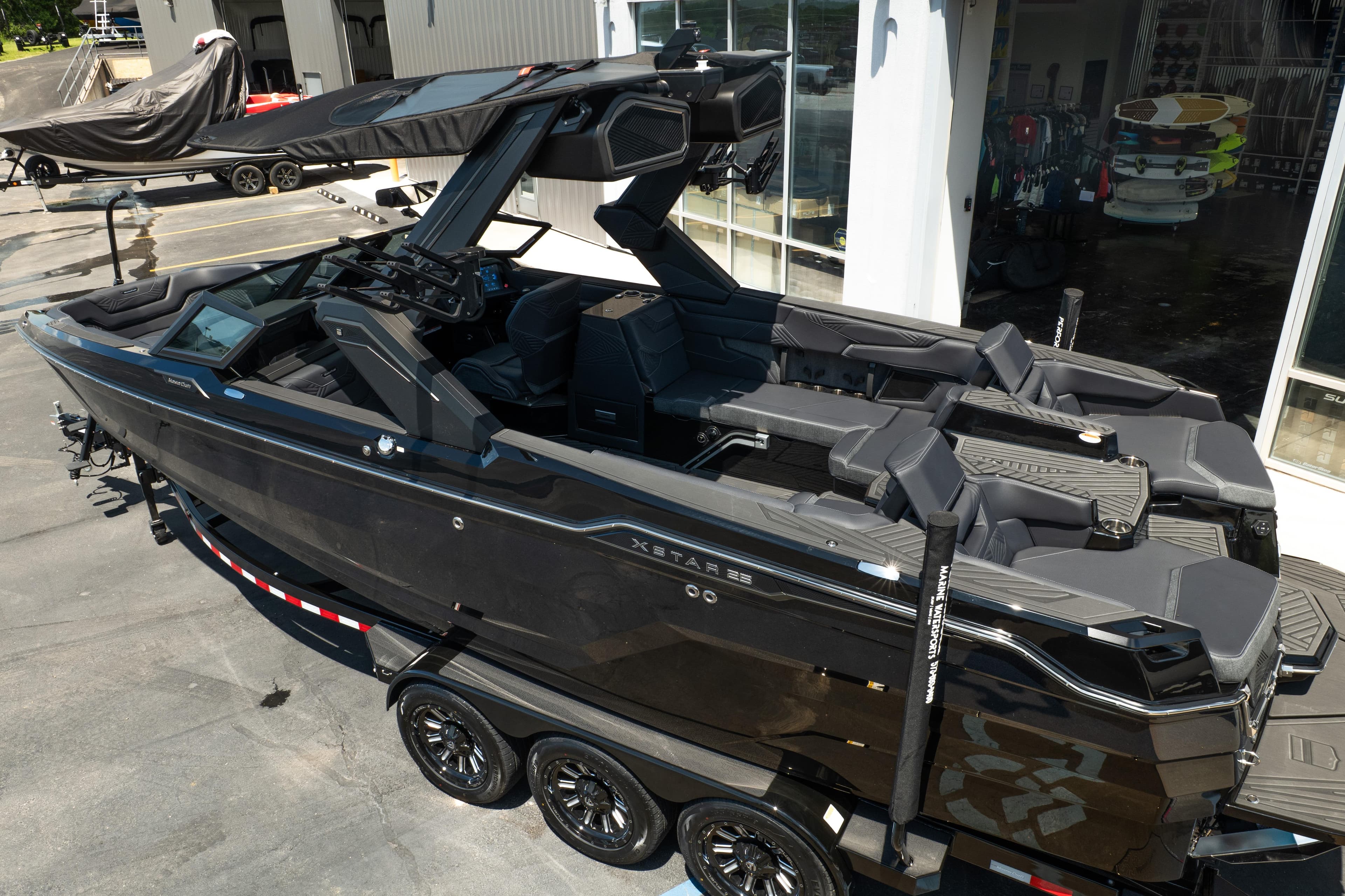 2026 MasterCraft XStar 25 boat on trailer, sleek black design, parked outside showroom.