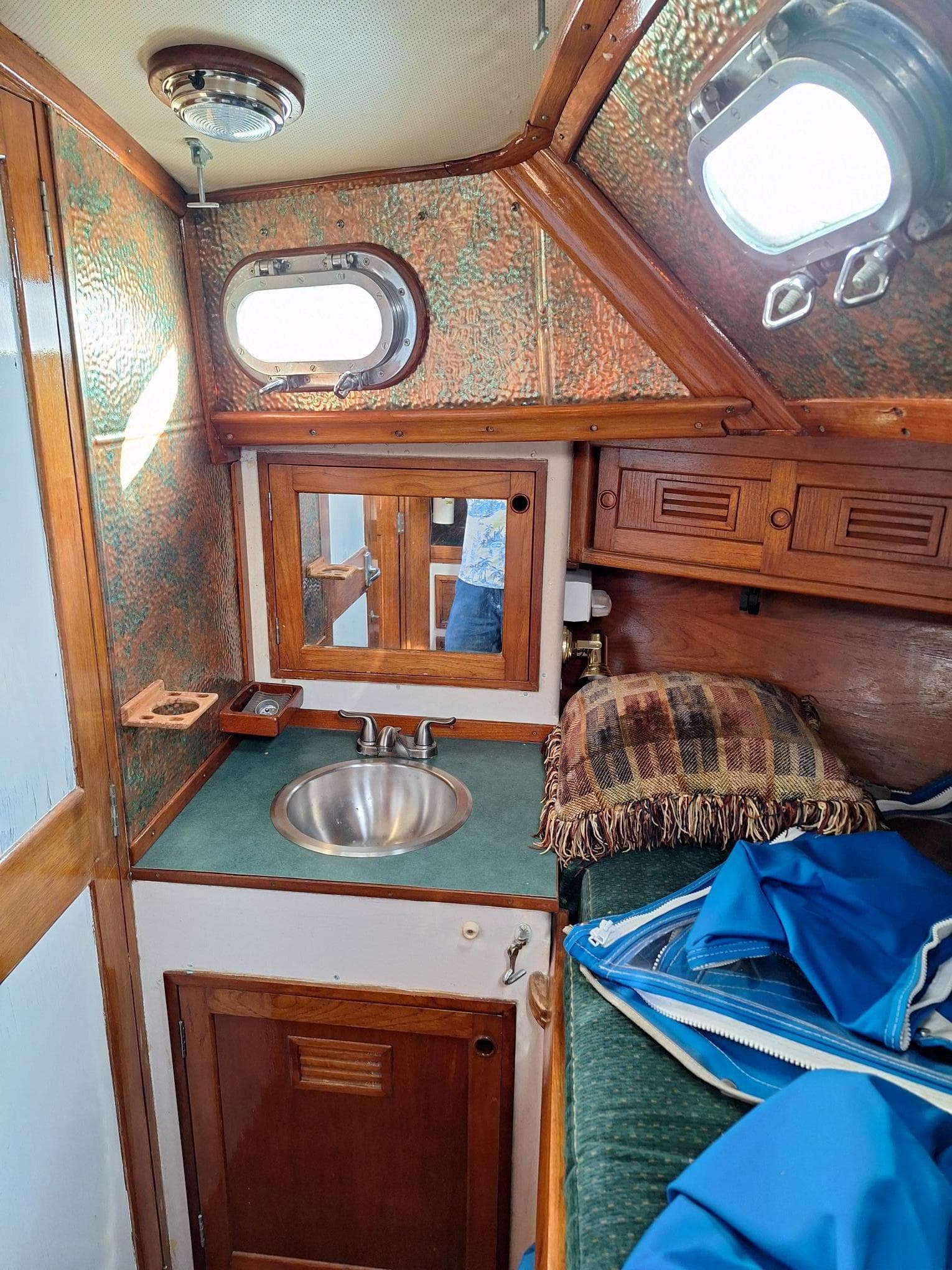 1976 Cheoy Lee 40 Center Cockpit interior with sink, portholes, and wooden cabinetry.