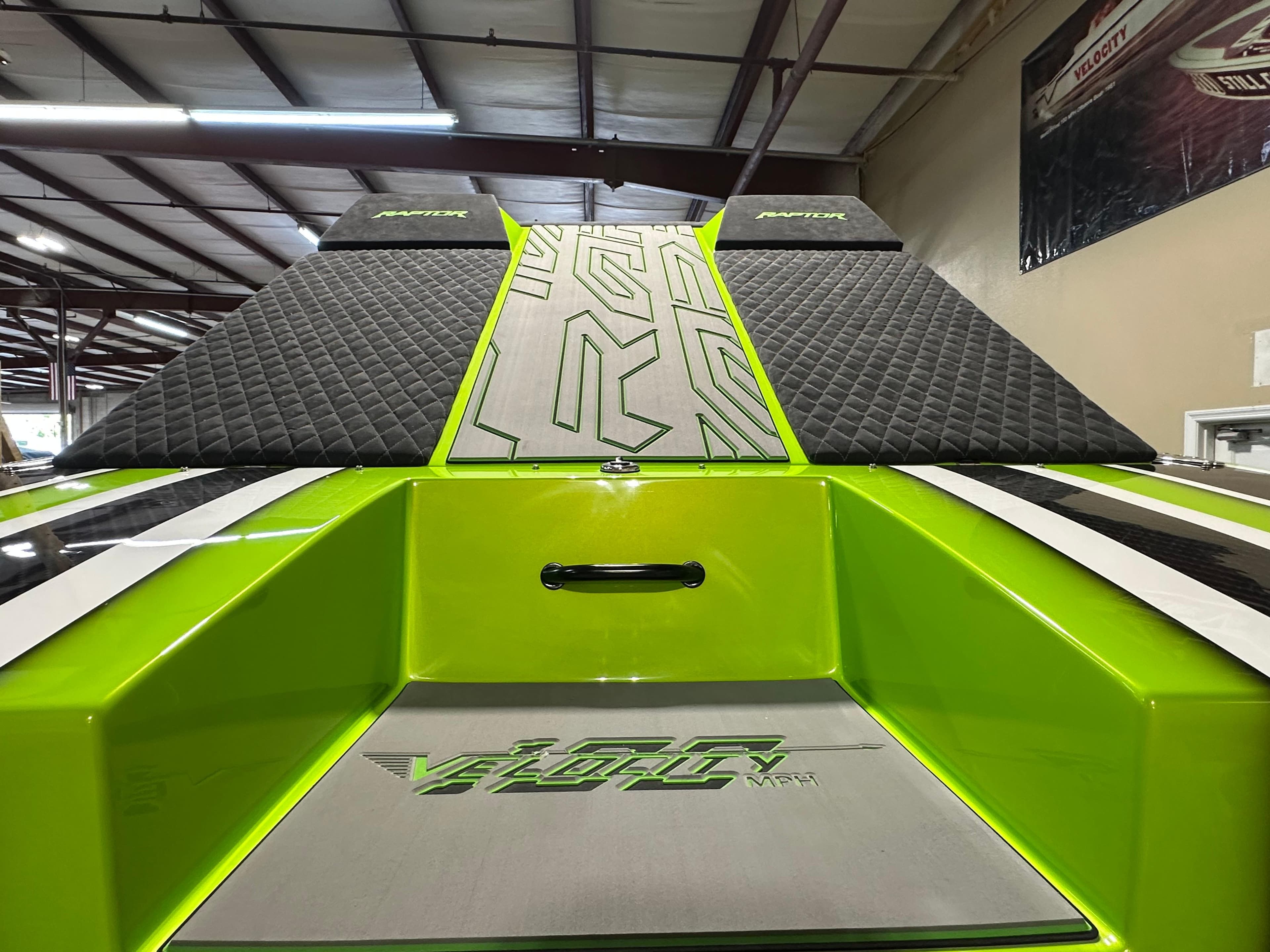 2025 Velocity 40 RAPTOR boat with vibrant green and black design in a showroom.