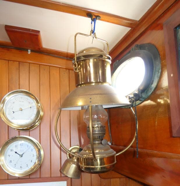 Vintage brass lantern and clocks inside a 1978 Brewer 45 Ketch sailboat cabin.