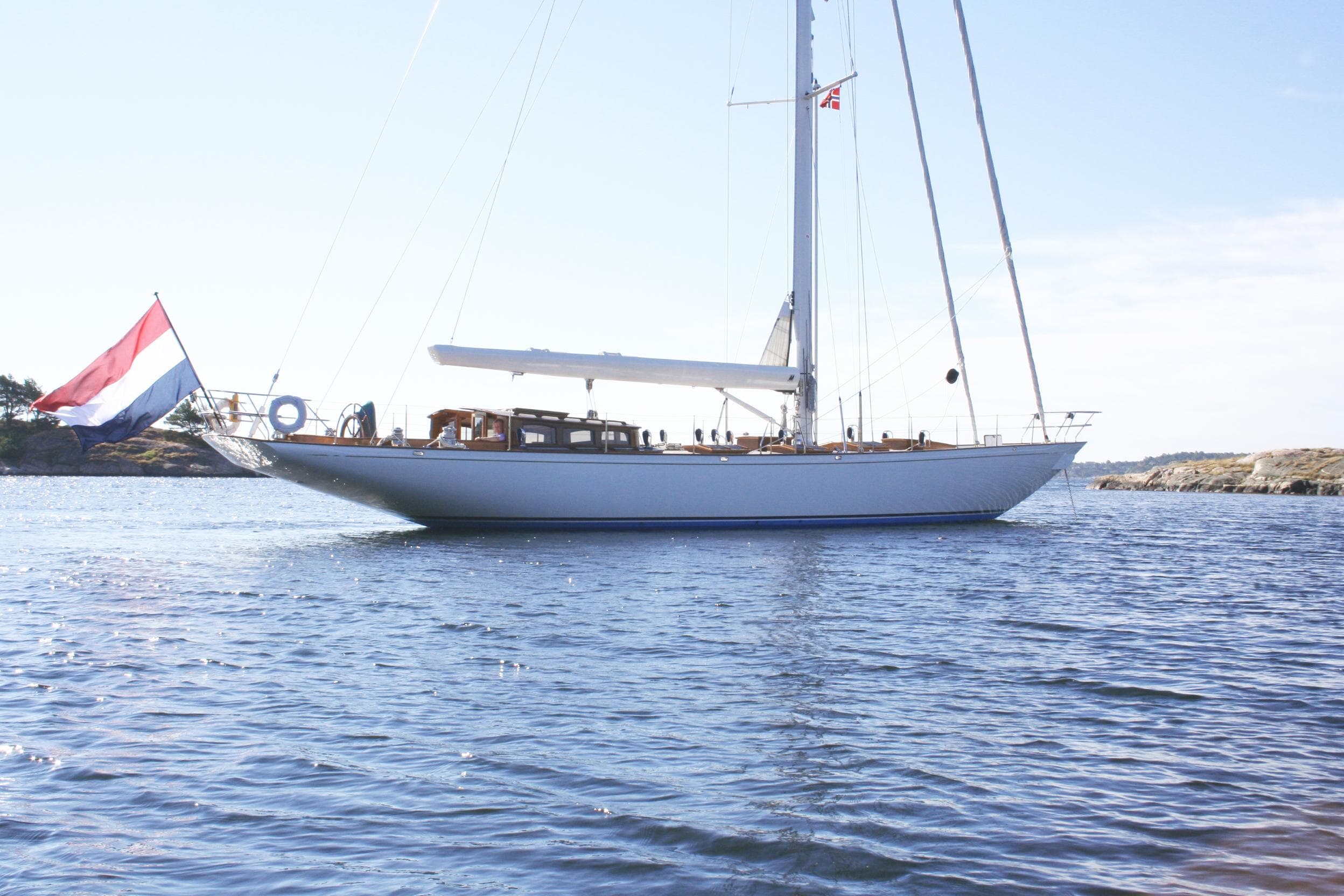Classic 2004 Hoek Classic 73 yacht sailing on calm waters with a flag.