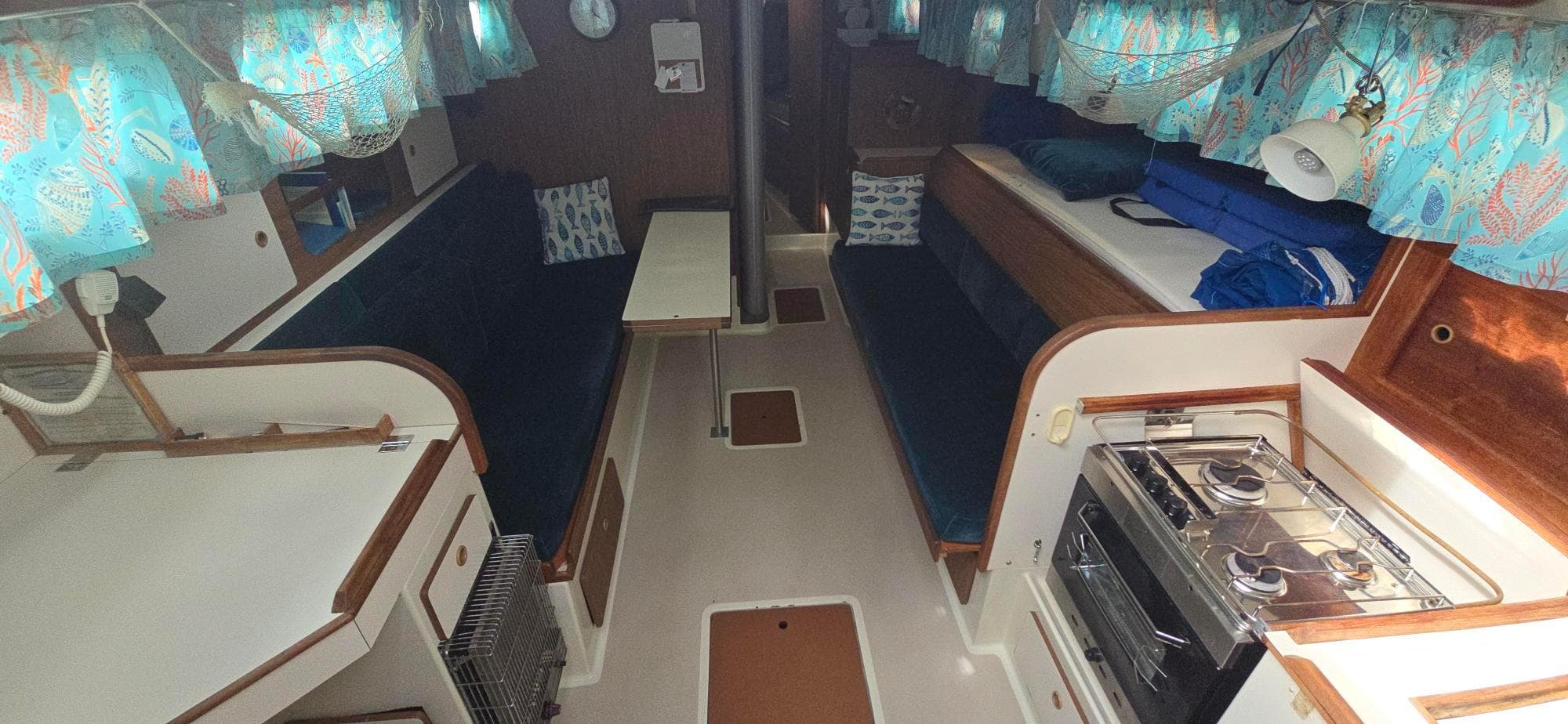Interior of a 1977 Pearson 39 sailboat with cozy seating and a compact kitchen.