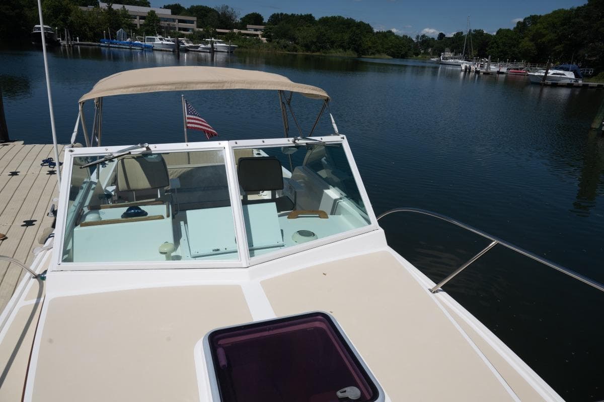 2004 Hunt Yachts Surfhunter 25 docked on a serene lake with American flag.