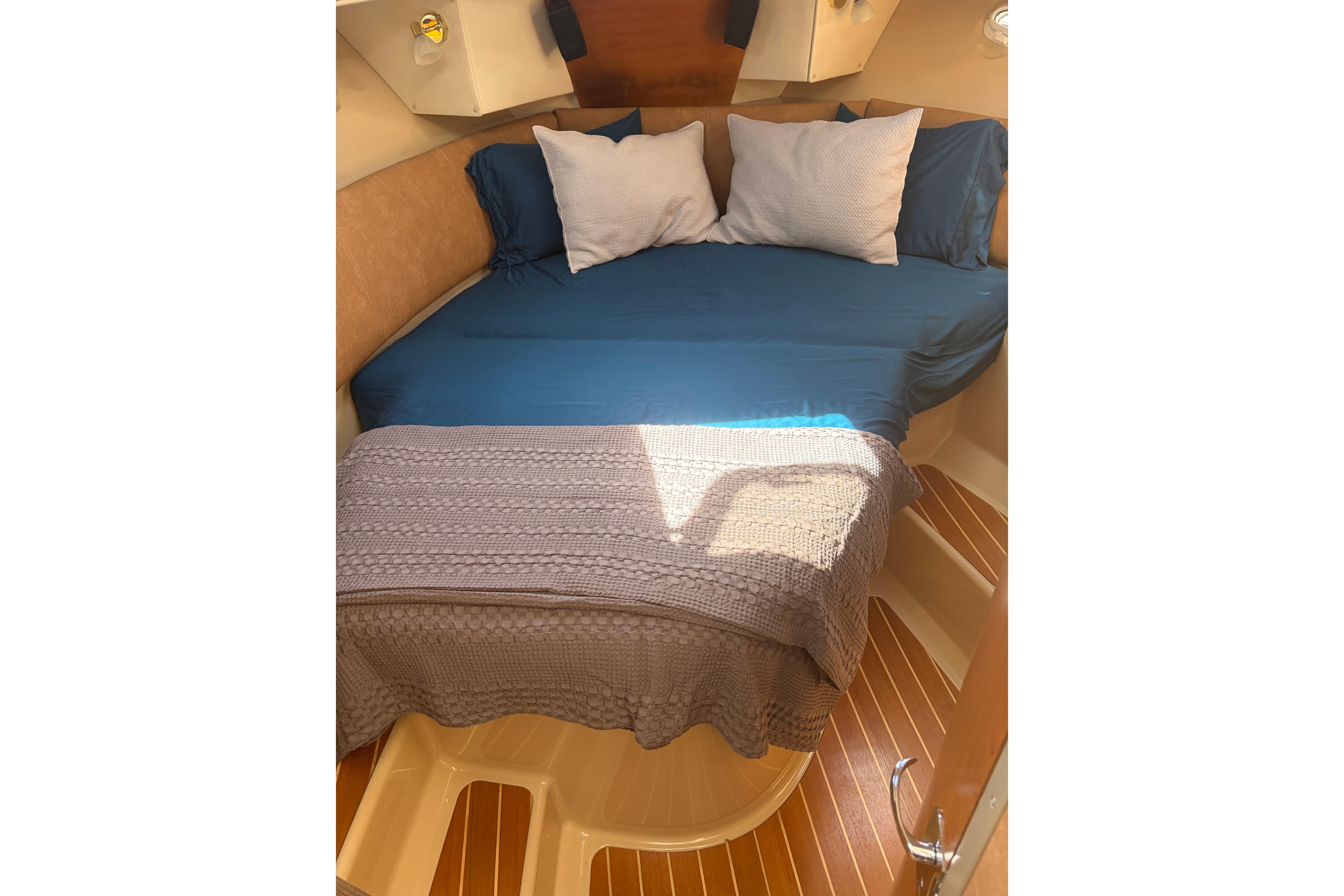Cozy cabin interior of 2014 Cutwater C-30 Sedan with blue bedding and wooden flooring.