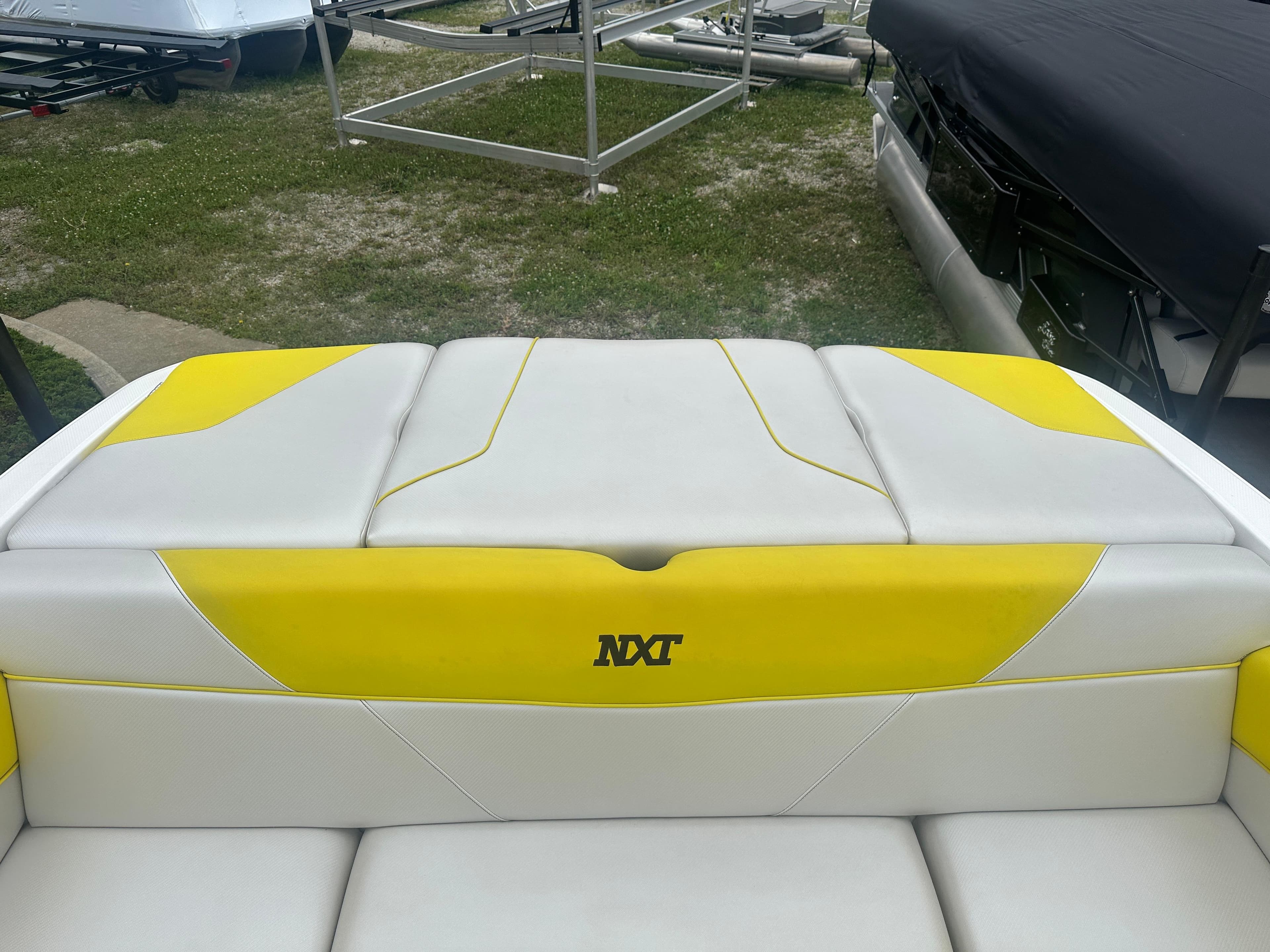 2018 MasterCraft NXT22 boat with yellow and white seating, parked on grass.