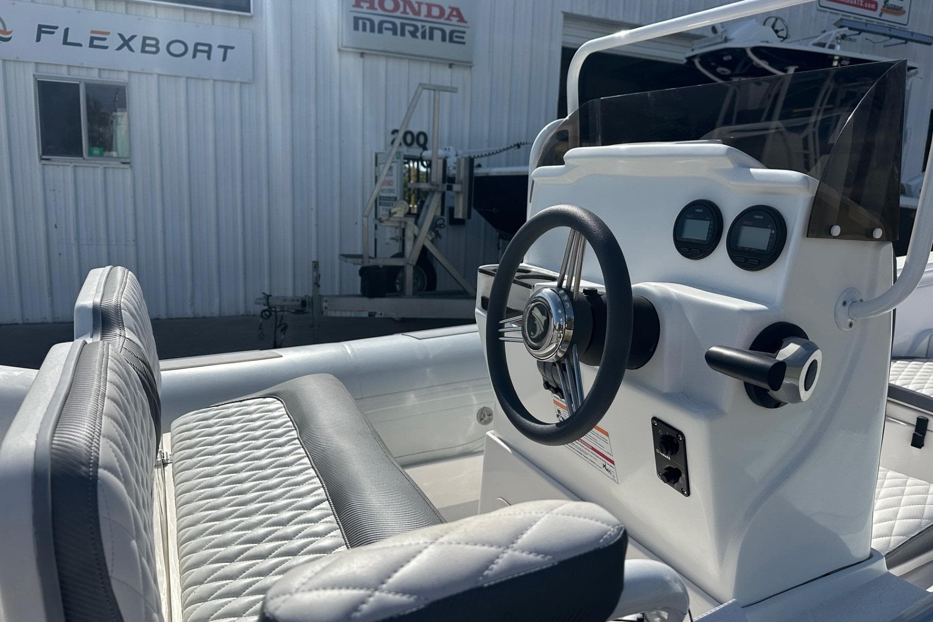 2024 Caribe DL-20S boat console with steering wheel and gauges, near Flexboat and Honda Marine signs.