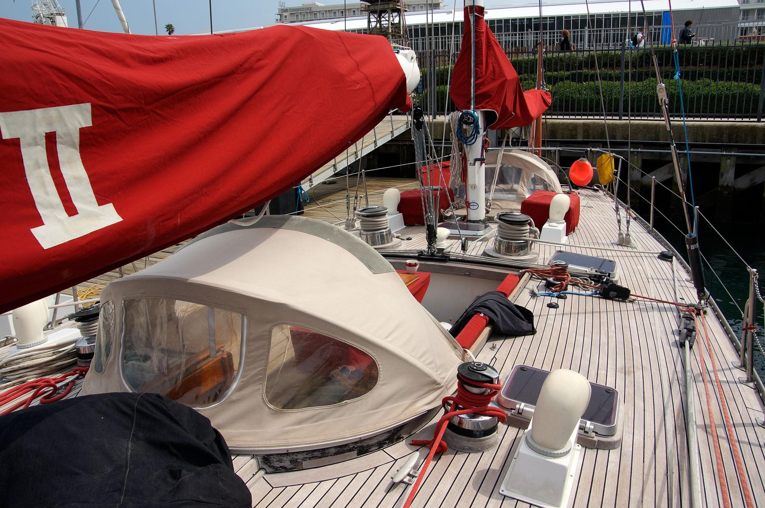 1980 Ketch Presles 72 sailboat deck with red sails and beige canopy.
