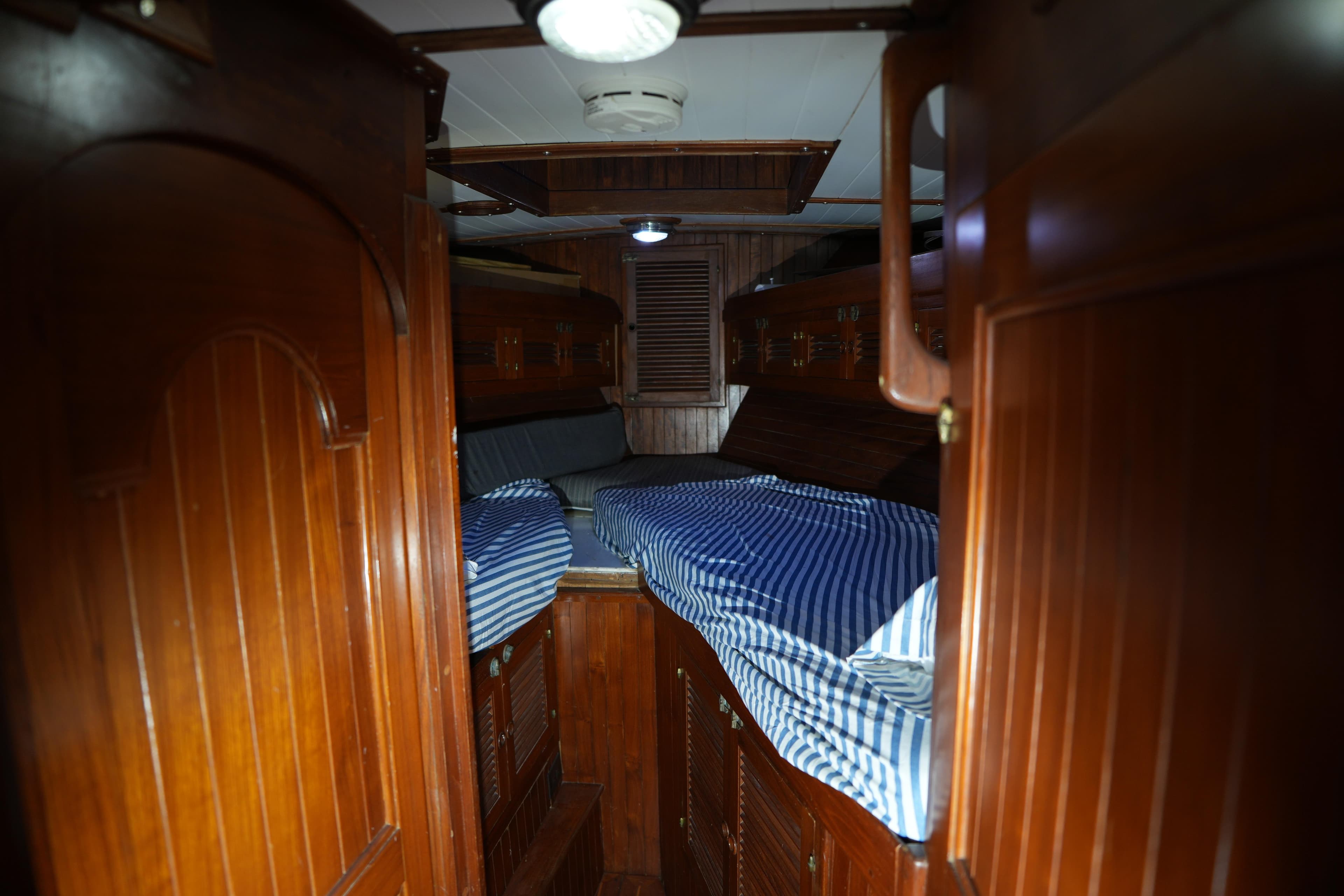 Cozy wooden cabin interior of 1982 Vagabond 47 sailboat with striped bedding.