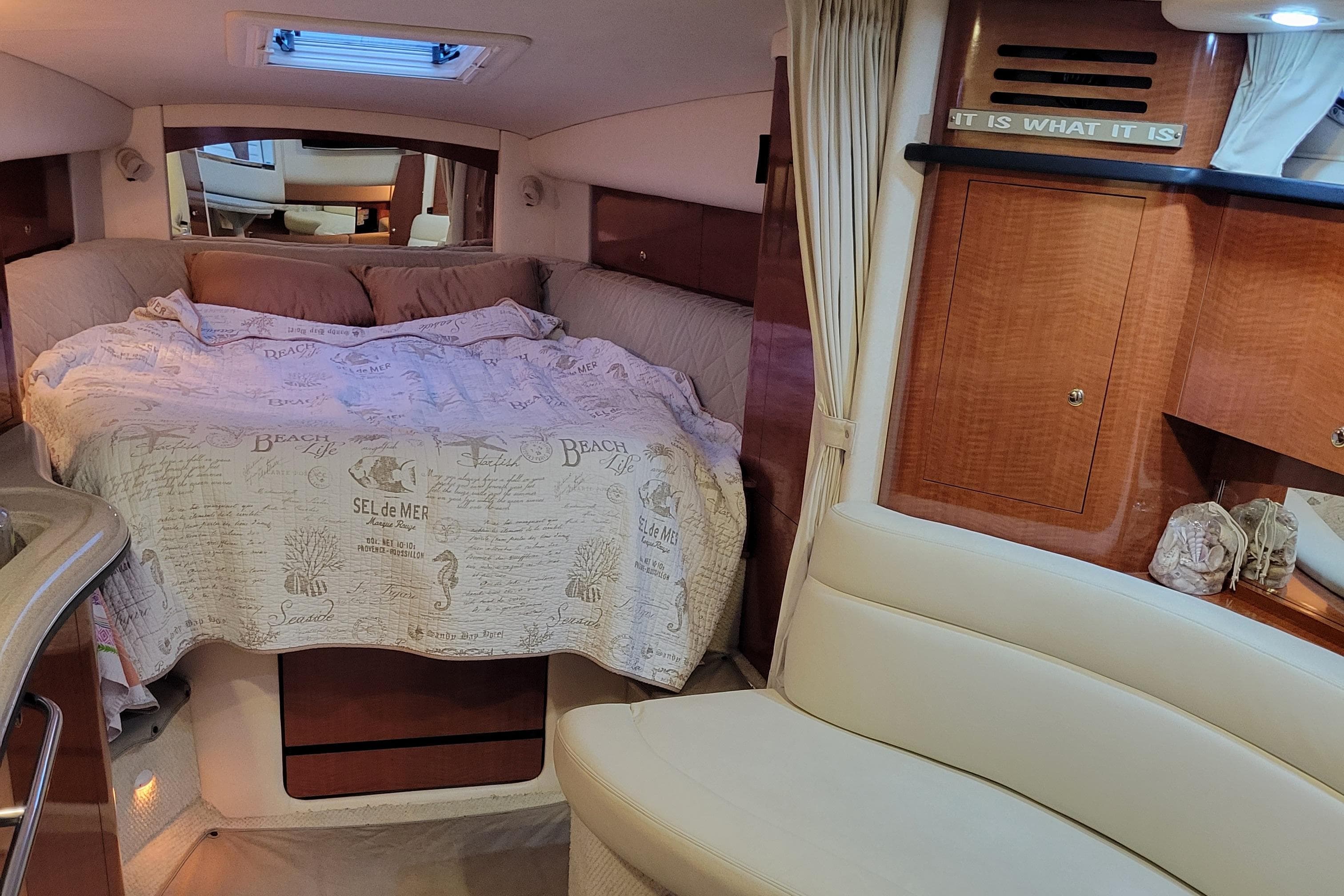 Interior of 2003 Sea Ray 320 Sundancer with cozy bed and wooden cabinetry.