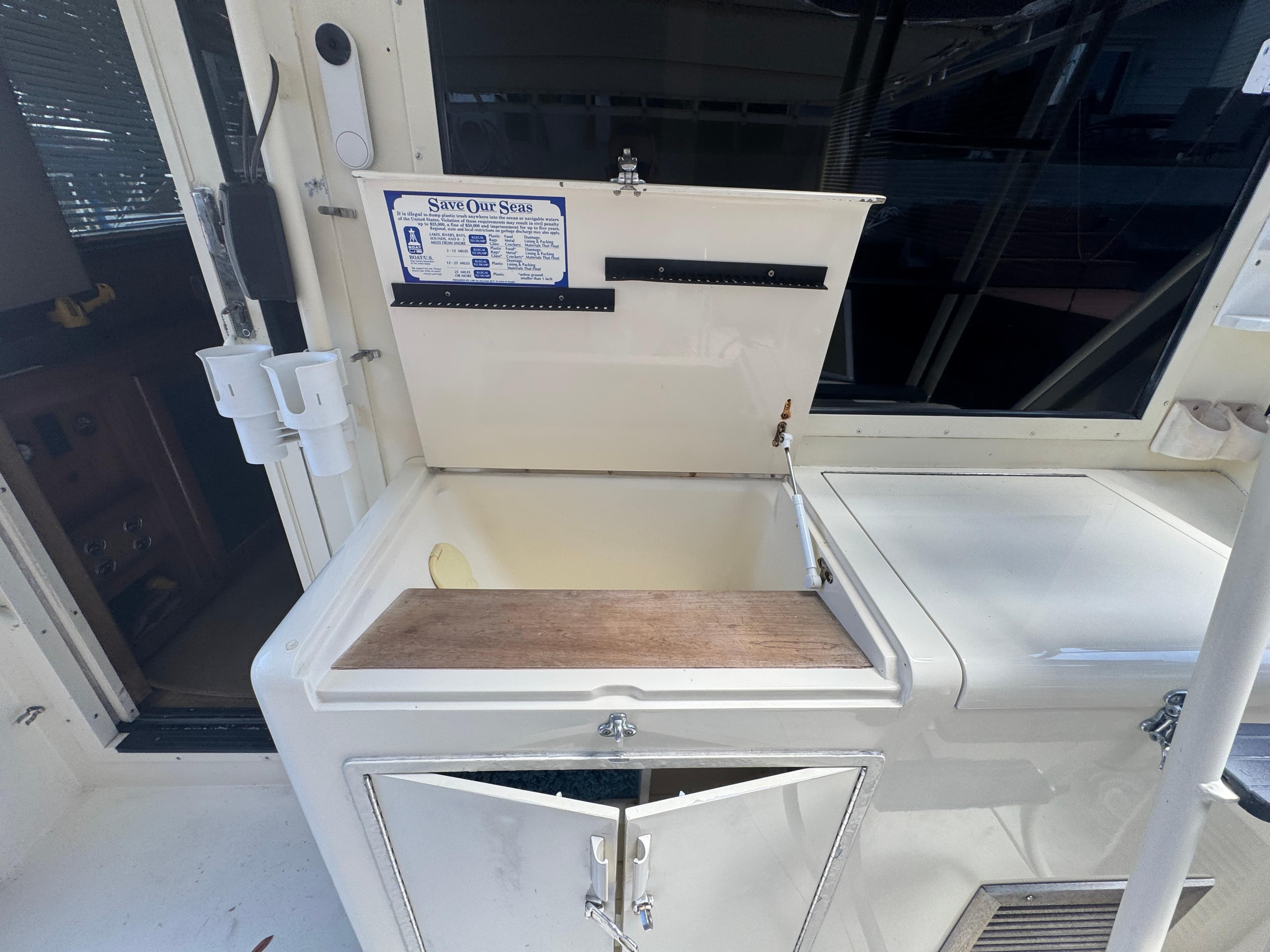 Open storage compartment on a 1990 Viking 35 boat, featuring a "Save Our Seas" sign.