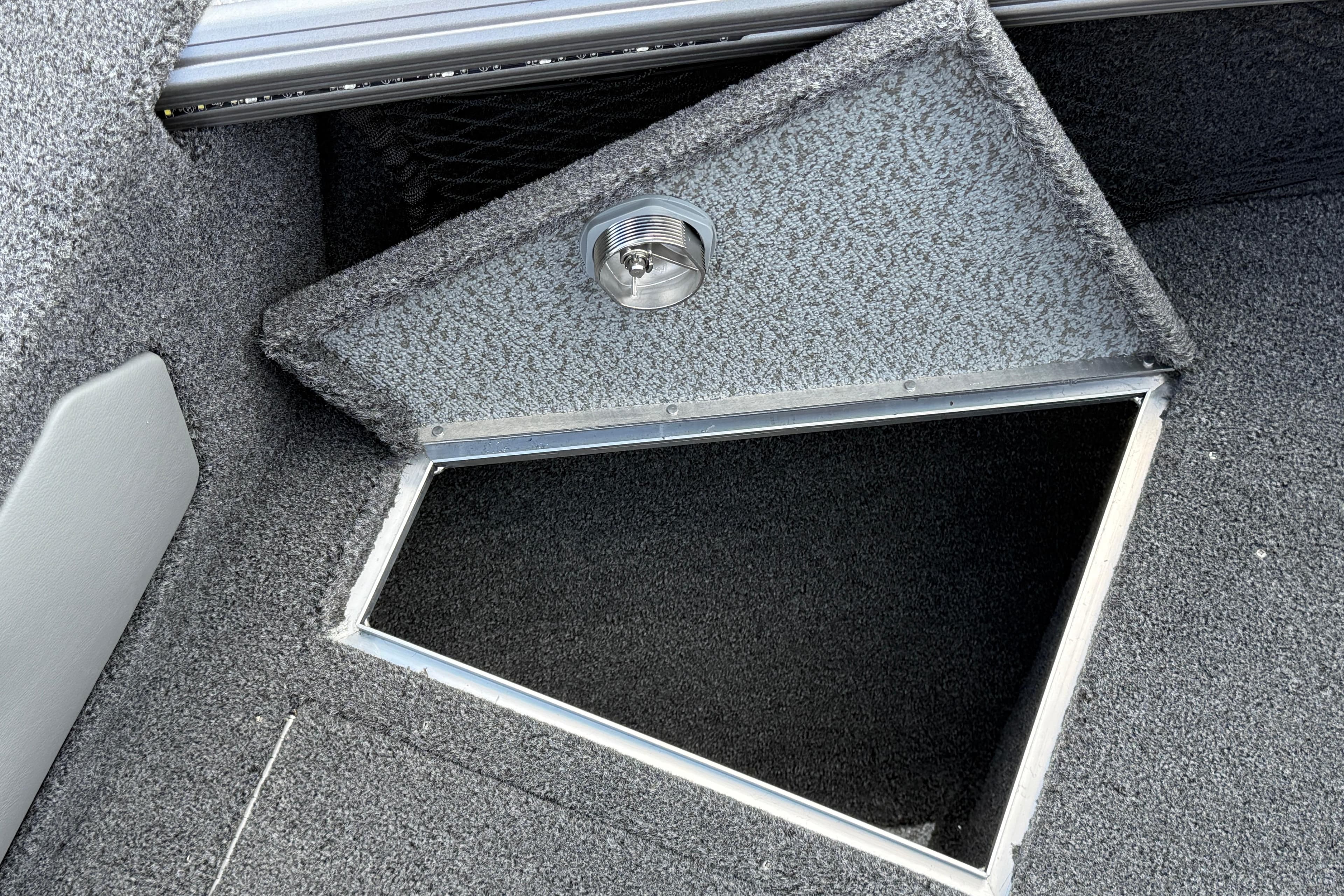 Open storage compartment in 2026 Lund 1975 Tyee boat, featuring carpeted interior and light.