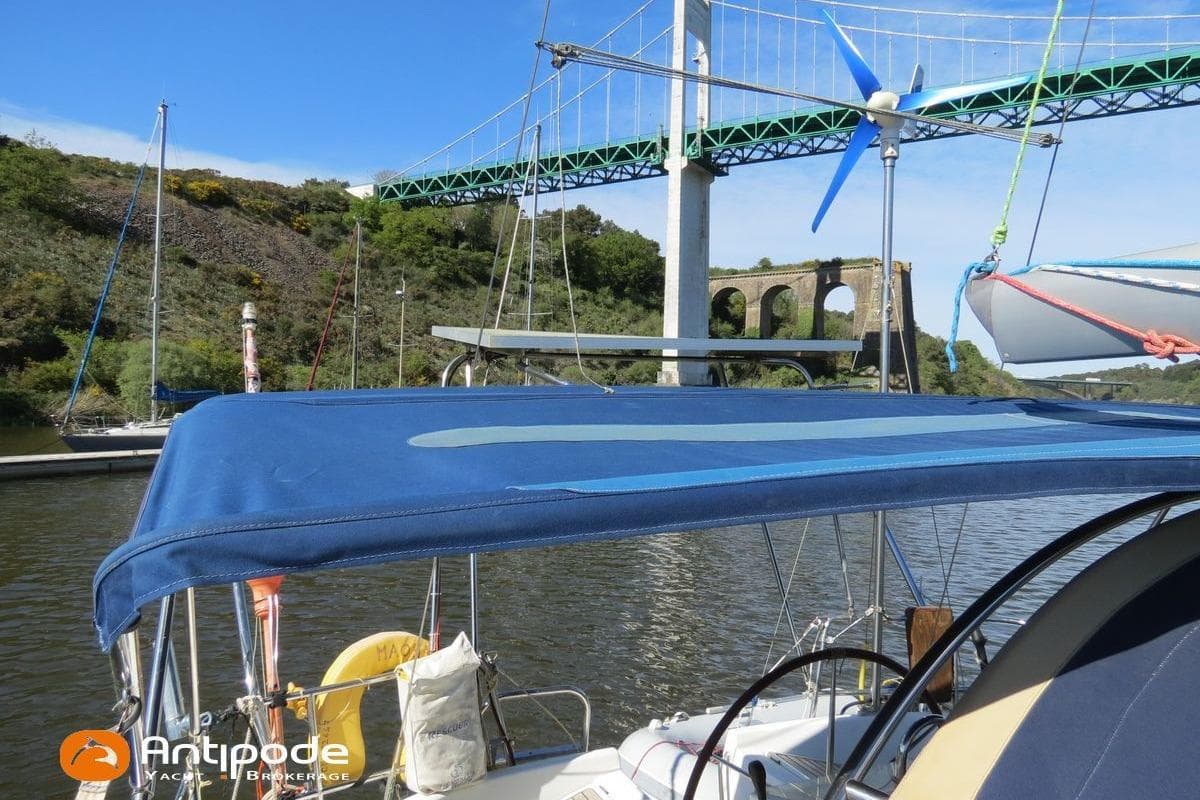 2003 Beneteau Oceanis 411 sailboat under bridge, featuring blue canopy and wind turbine.
