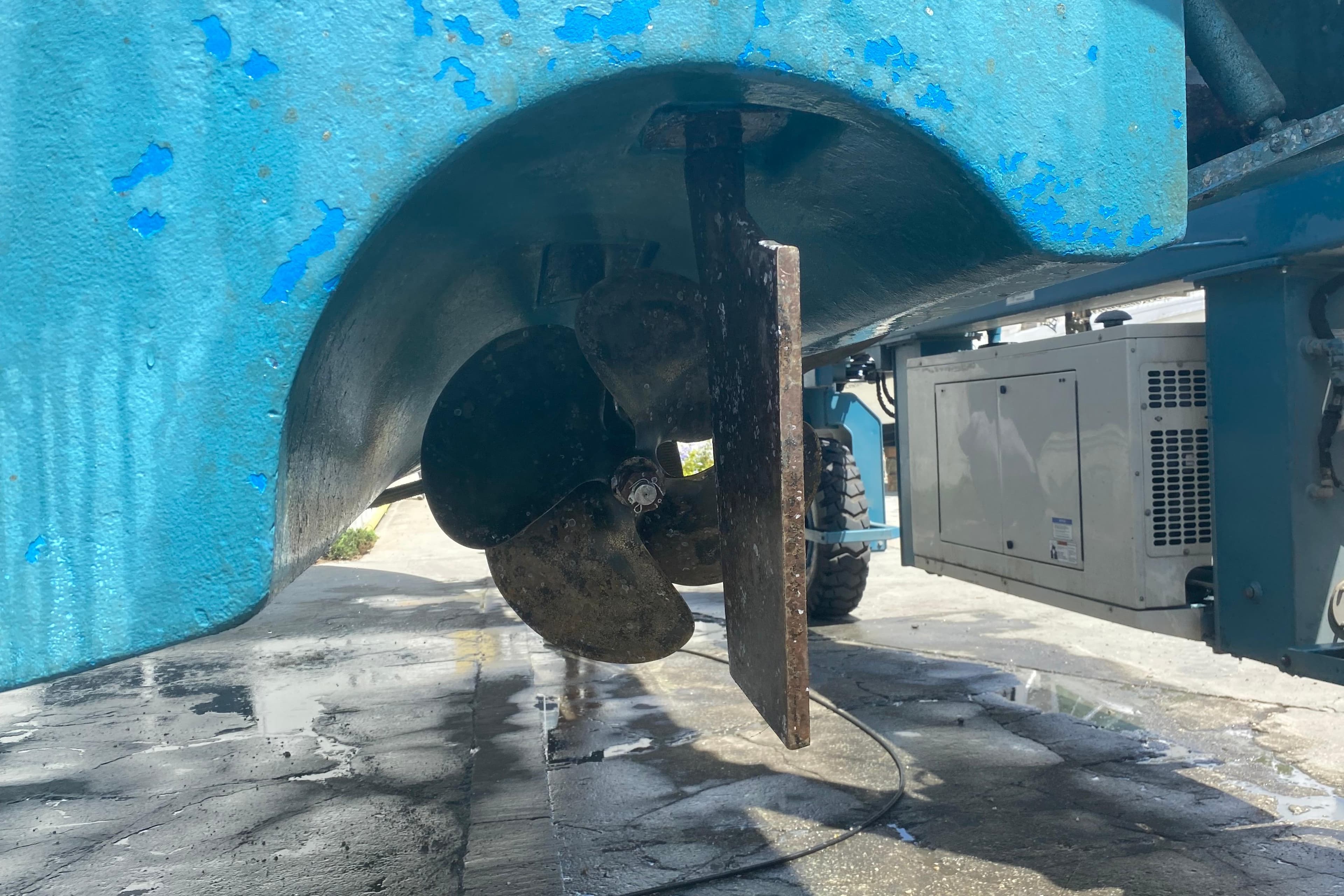 Close-up of a 2005 Formula boat propeller and rudder, showing wear and blue paint.