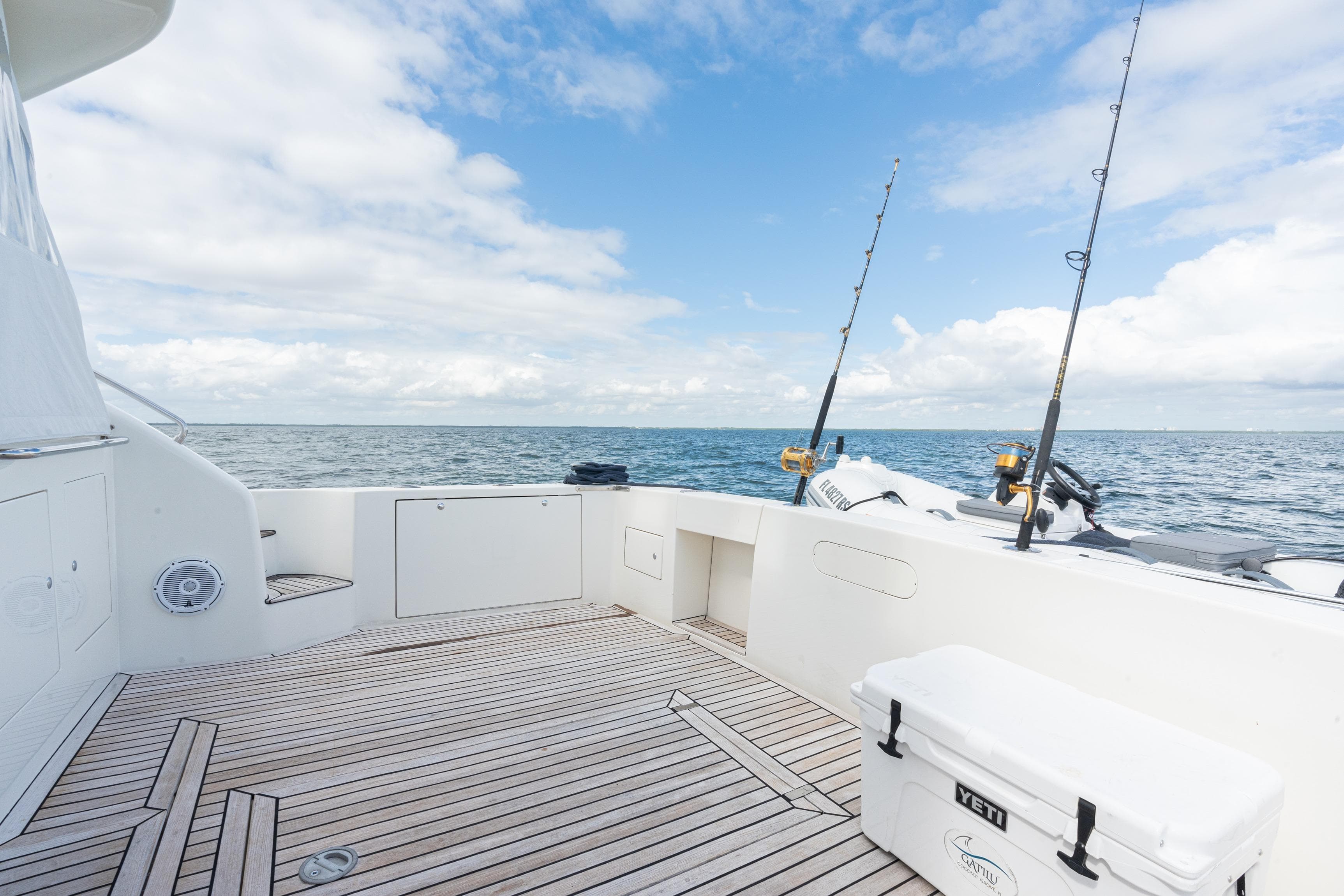 Spacious deck of 2001 Uniesse 48 Open yacht with fishing rods, ocean view.