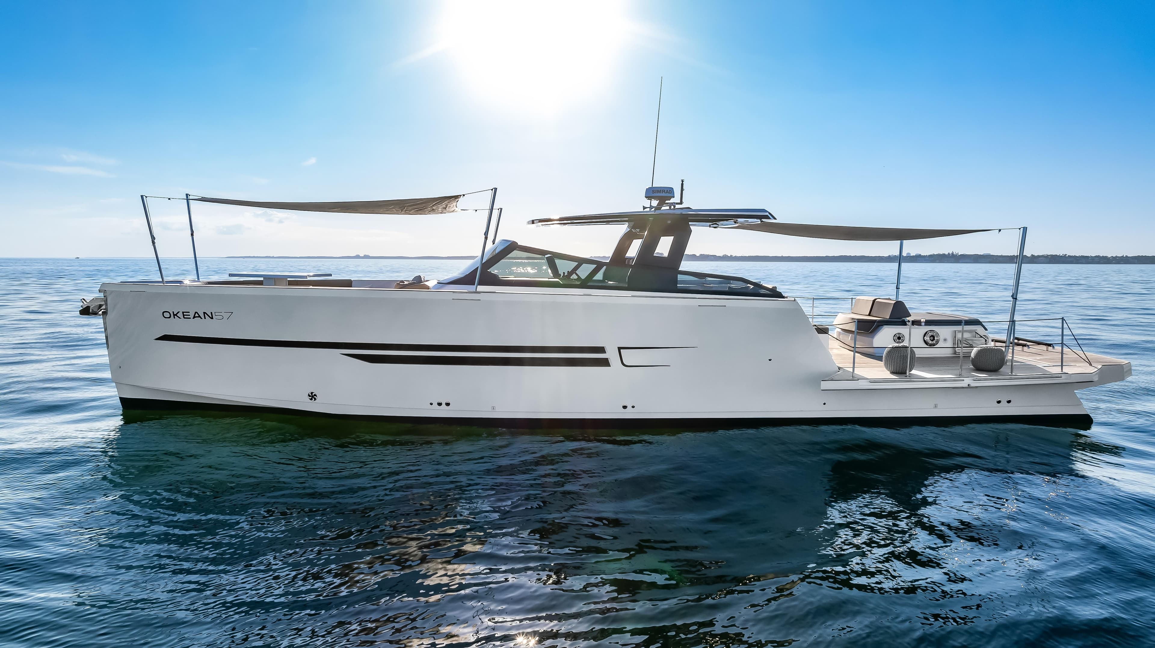 Luxury OKEAN 57 yacht cruising on open water under clear blue sky, 2026 model.