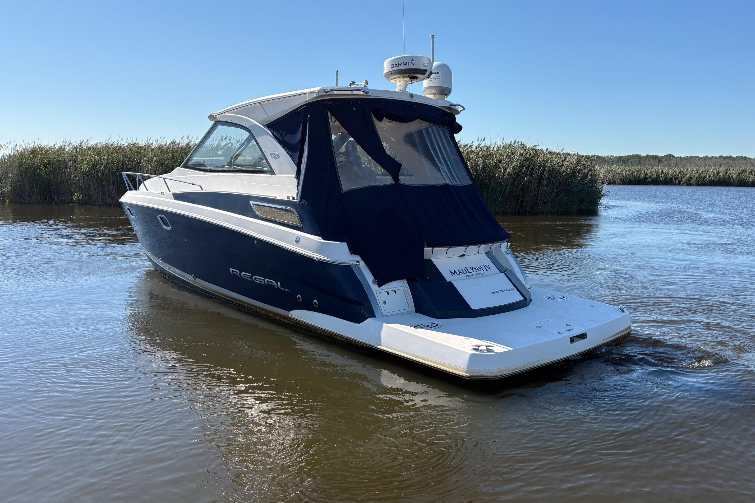 2013 Regal 35 Sport Coupe boat on calm water, surrounded by reeds.