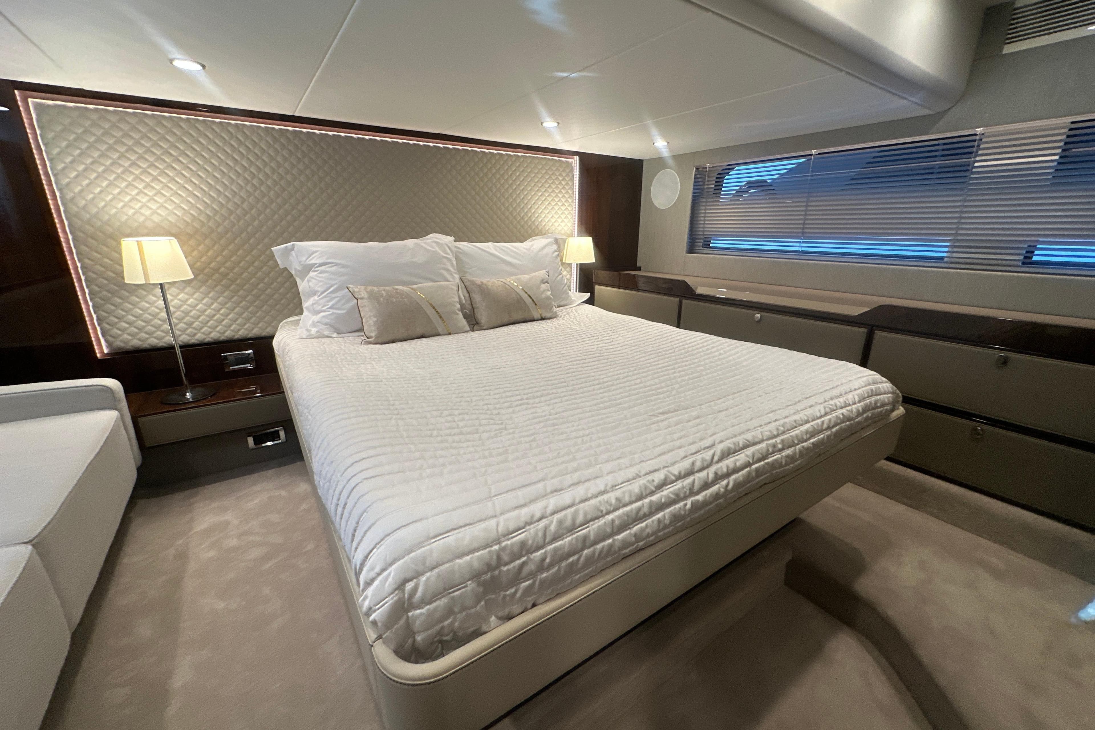 Luxurious bedroom interior of 2024 Fairline Squadron 50 yacht with elegant bedding and ambient lighting.