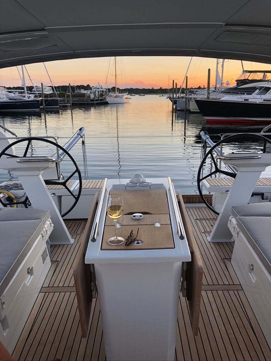 Beneteau Oceanis 51.1 yacht deck at sunset, featuring a table with wine.