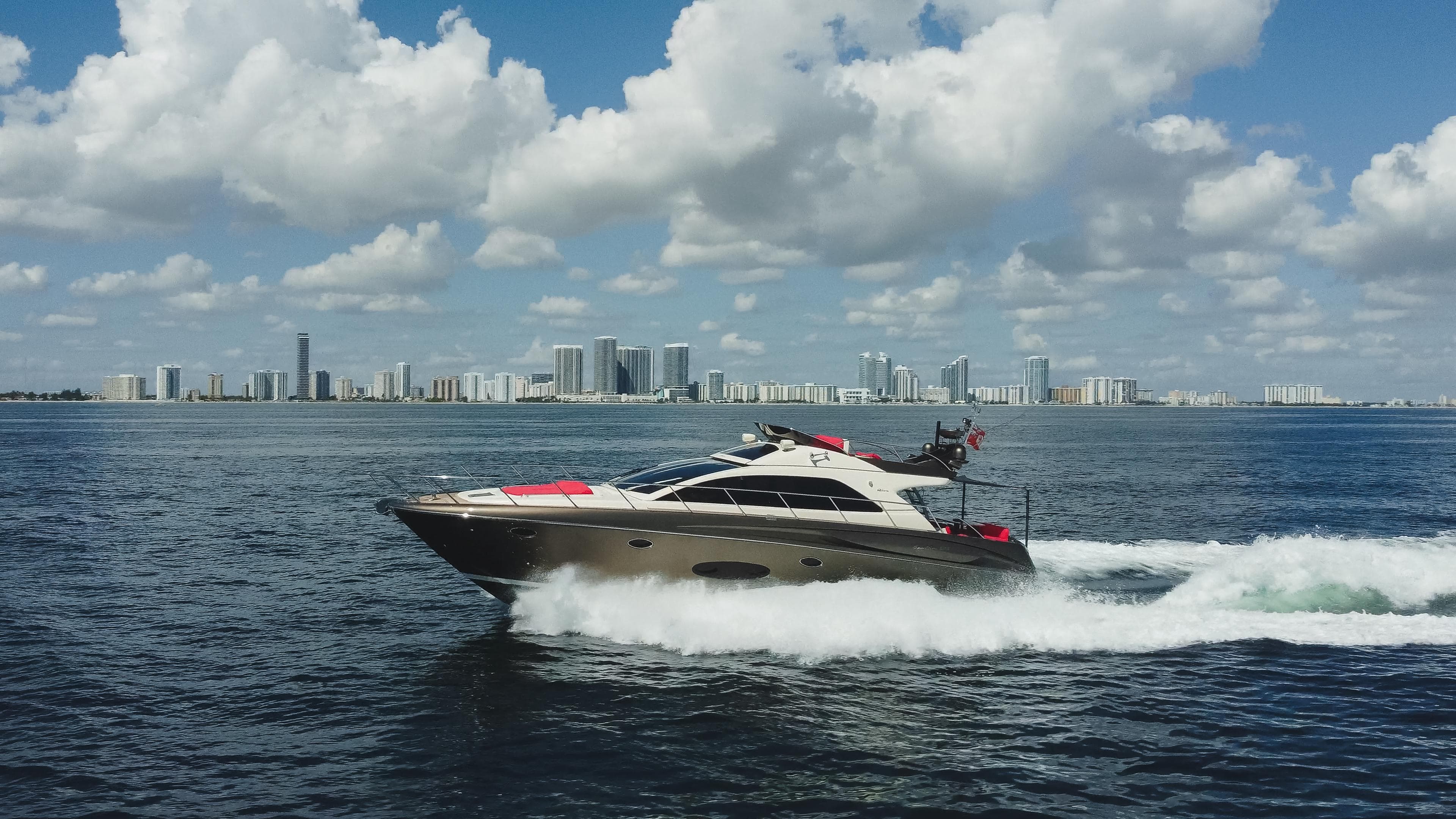 2011 Riva SportRiva 56 yacht cruising on open water with city skyline in background.