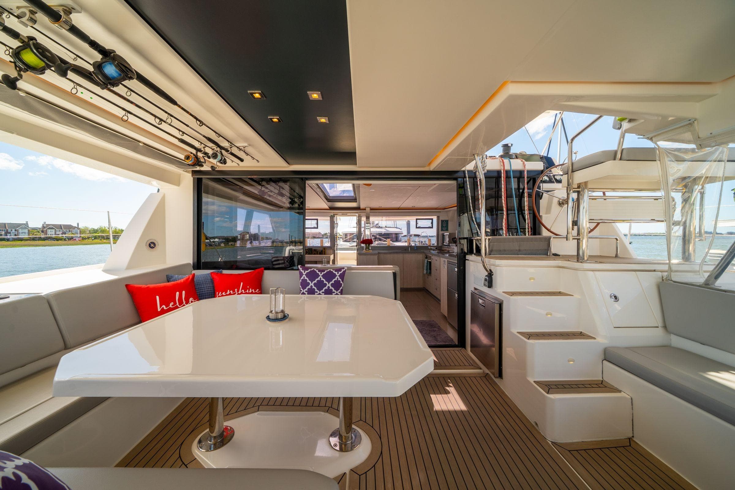 Luxurious 2020 Leopard 45 yacht interior with dining area, fishing rods, and scenic water view.