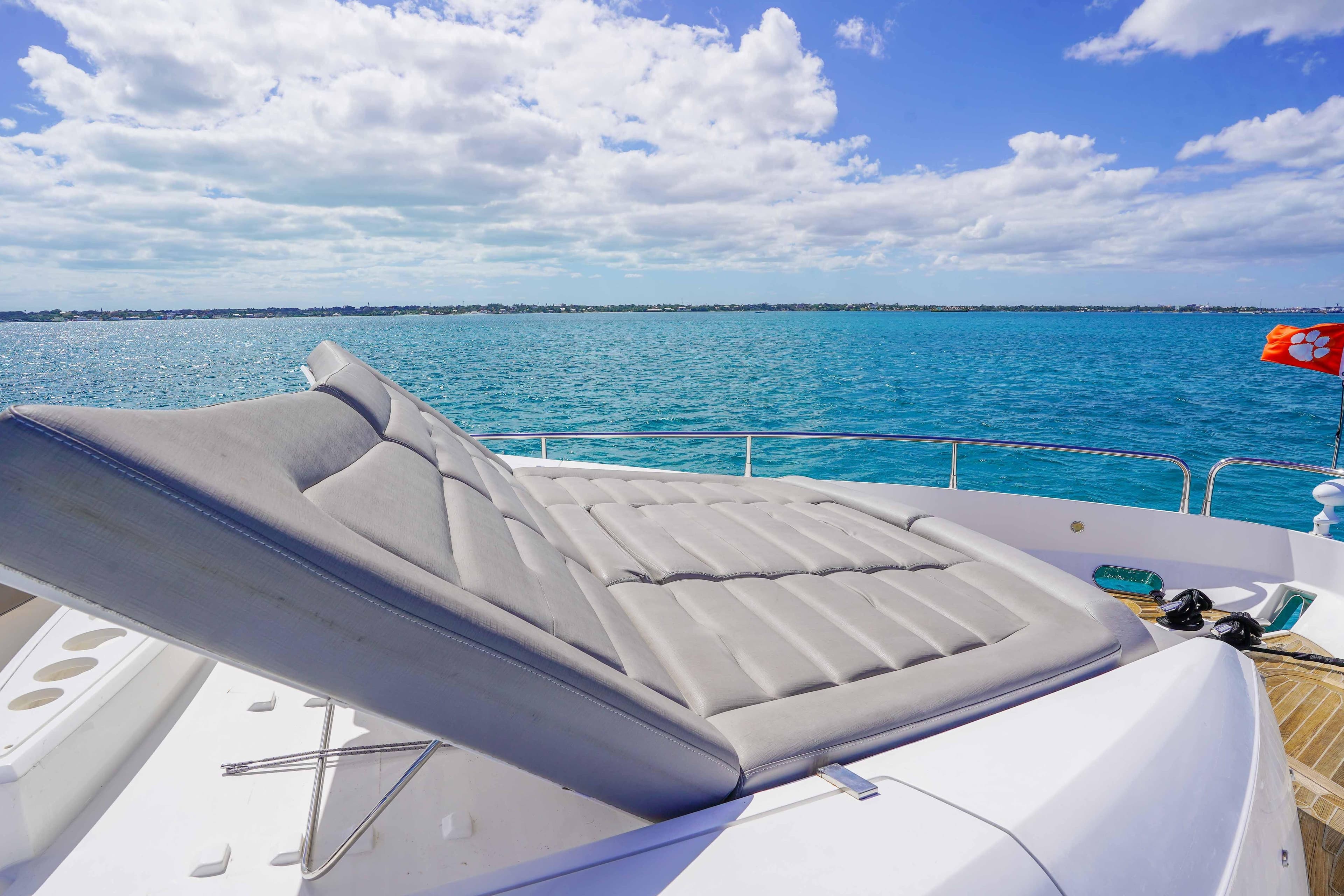 Luxurious 2016 Sunseeker 75 Yacht with sunbed, cruising on clear blue waters.
