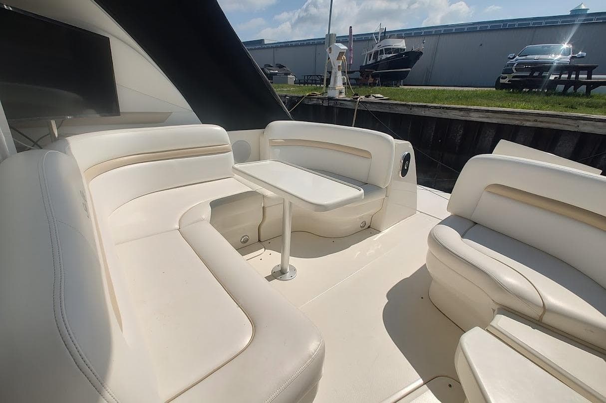2009 Sea Ray 380 Sundancer yacht interior with white seating and table, docked outdoors.