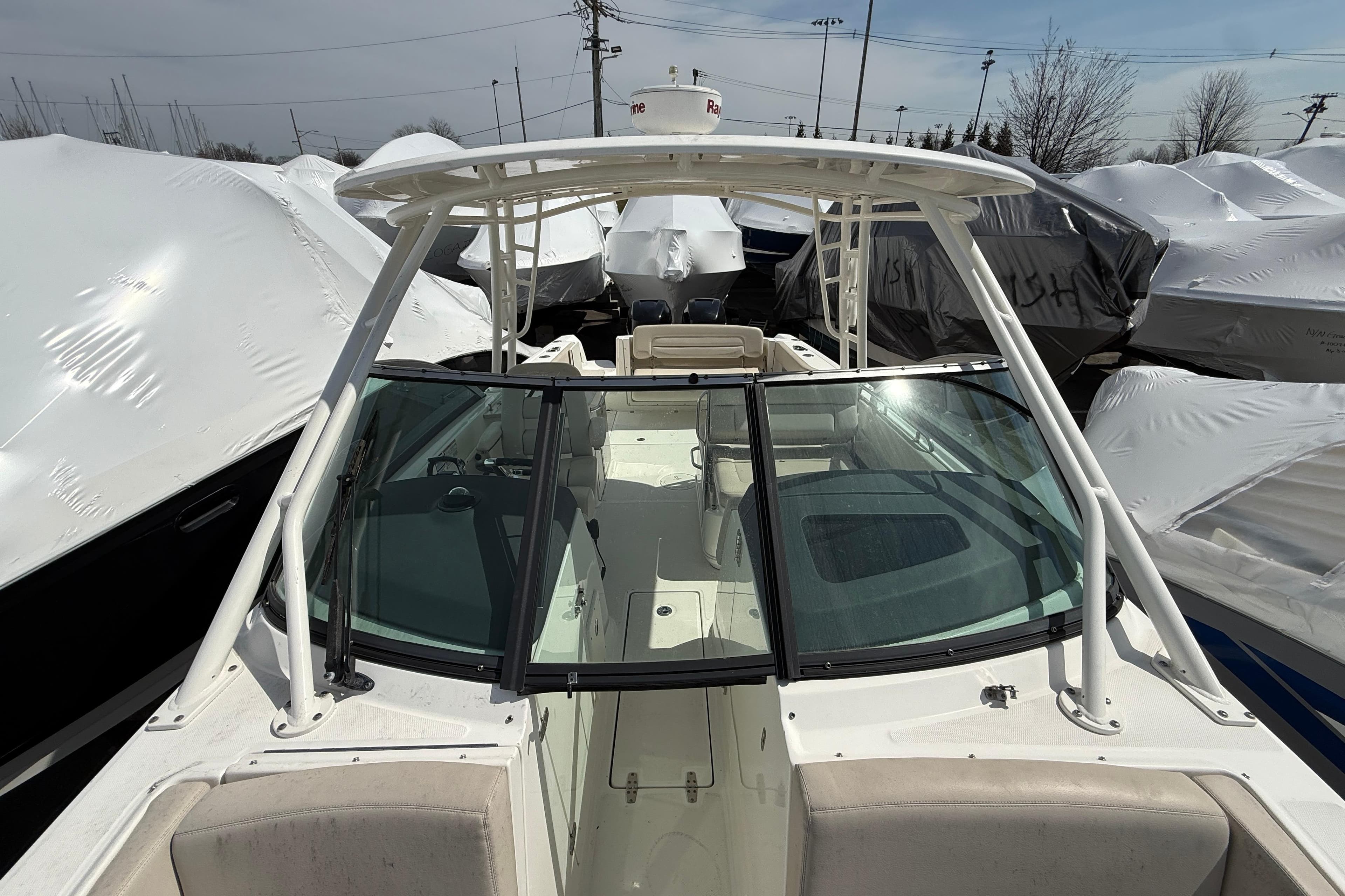2016 Boston Whaler 270 Vantage boat docked, surrounded by covered vessels.