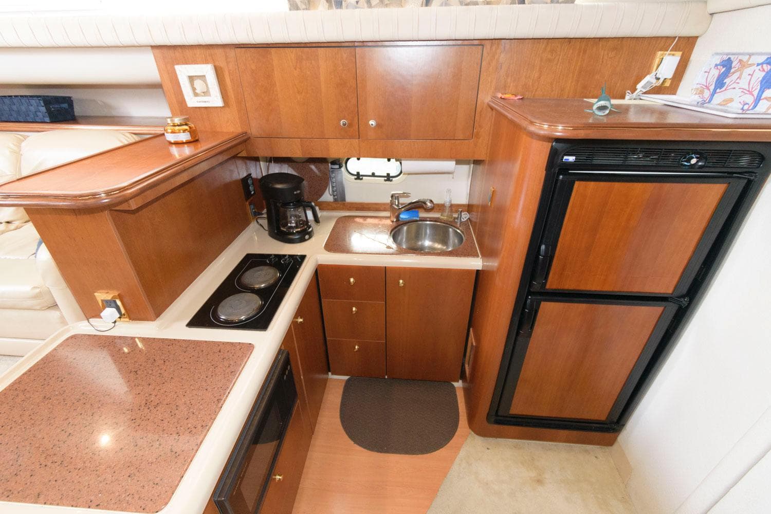 1999 Cruisers Yachts 3750 Motoryacht kitchen with wood cabinetry, sink, stove, and refrigerator.
