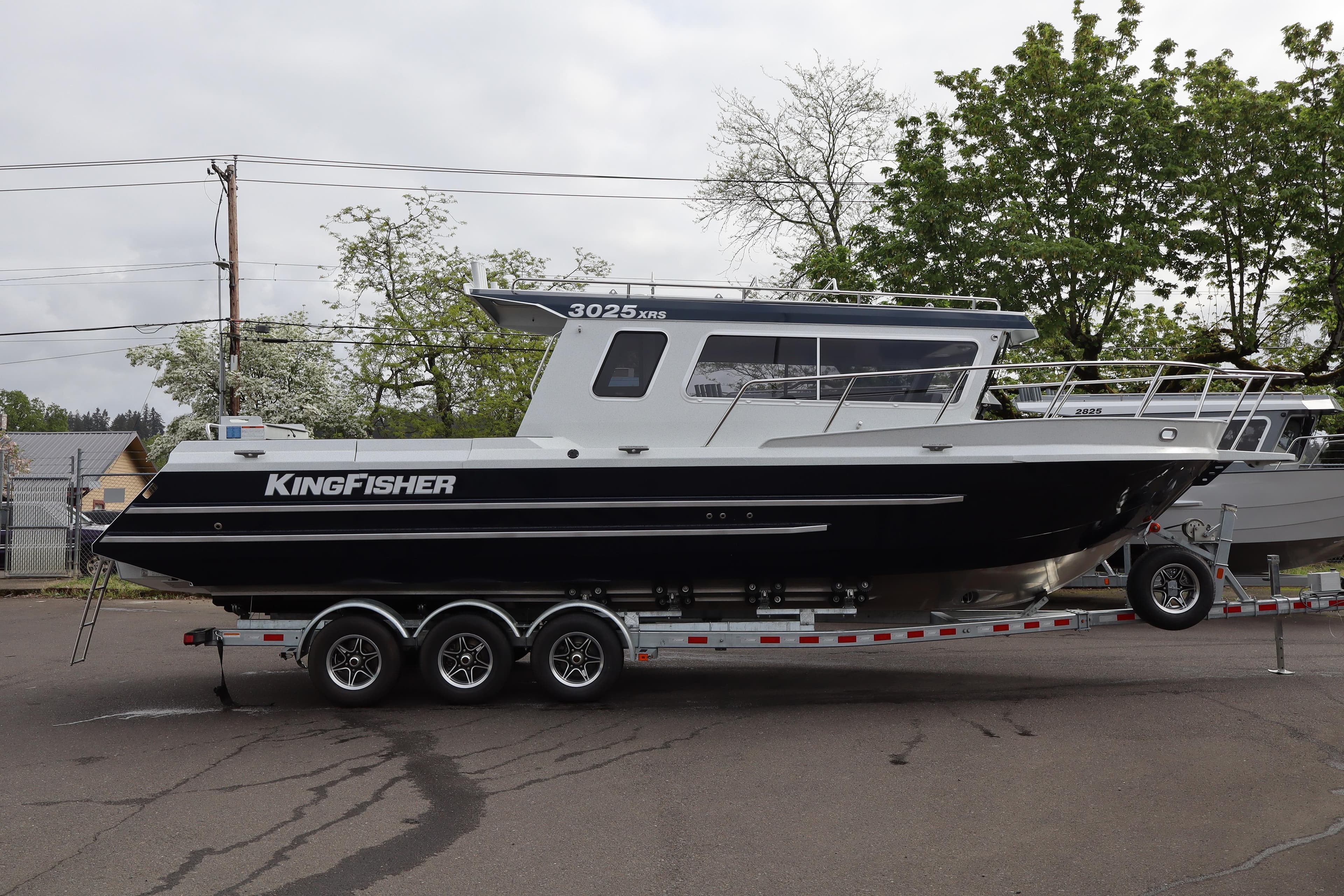 2026 KingFisher 3025 XRS boat on trailer, parked outdoors with trees in background.