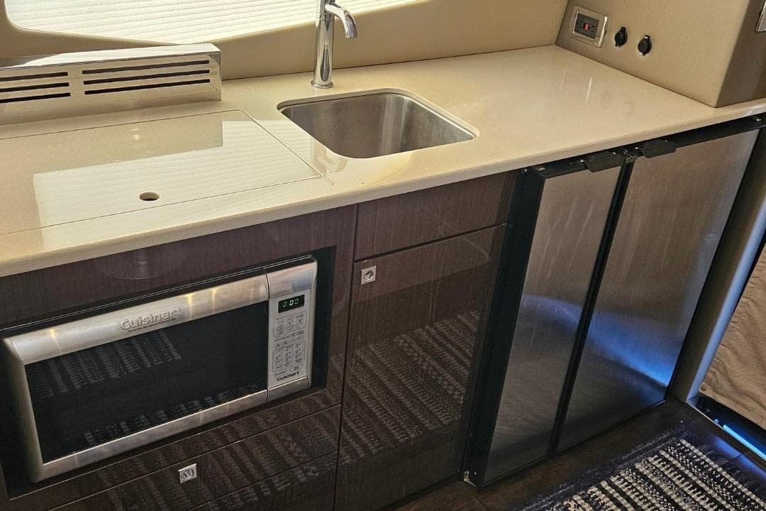 Modern kitchen area in 2020 Carver C37 Coupe with sink, microwave, and fridge.