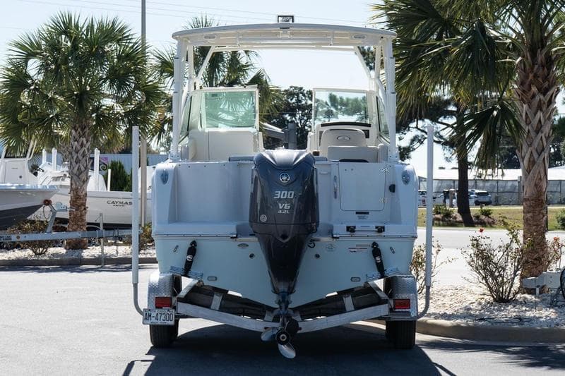 2023 Sailfish 245 DC boat with 300 V6 engine on trailer, surrounded by palm trees.