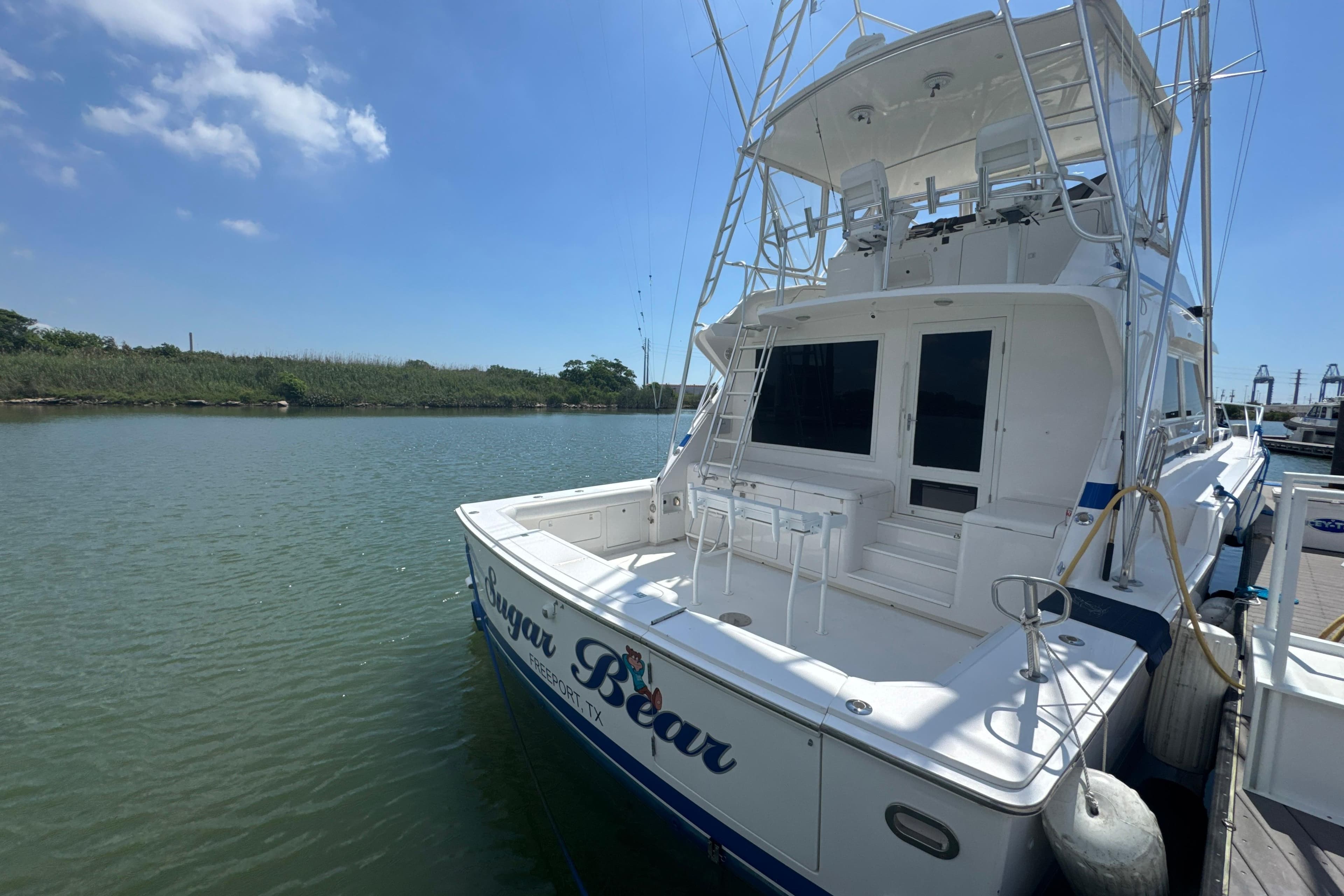1997 Bertram 54 Convertible yacht docked on a sunny day, featuring spacious deck and fishing equipment.