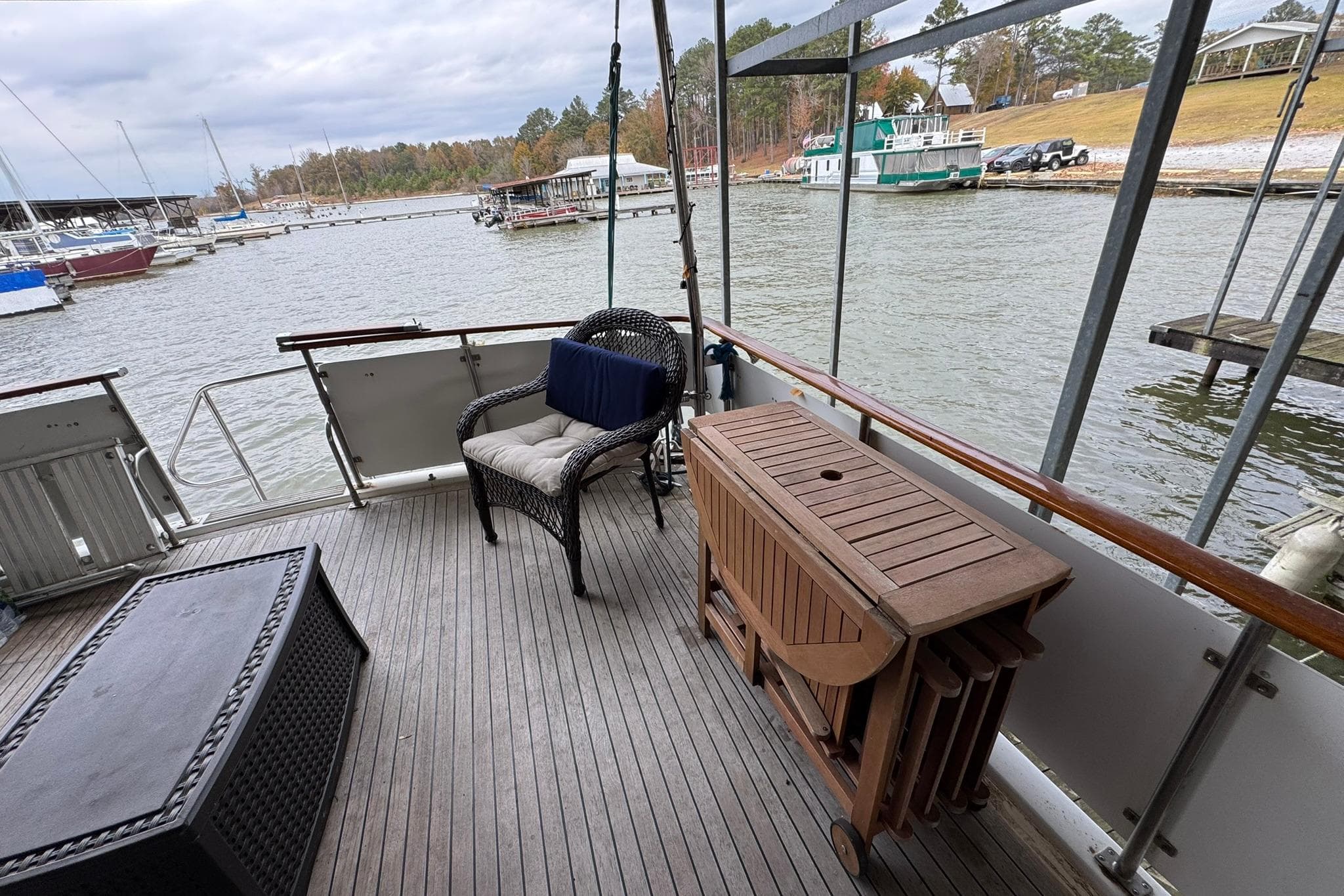 1991 DeFever 44 yacht deck with wicker chair, table, and scenic marina view.