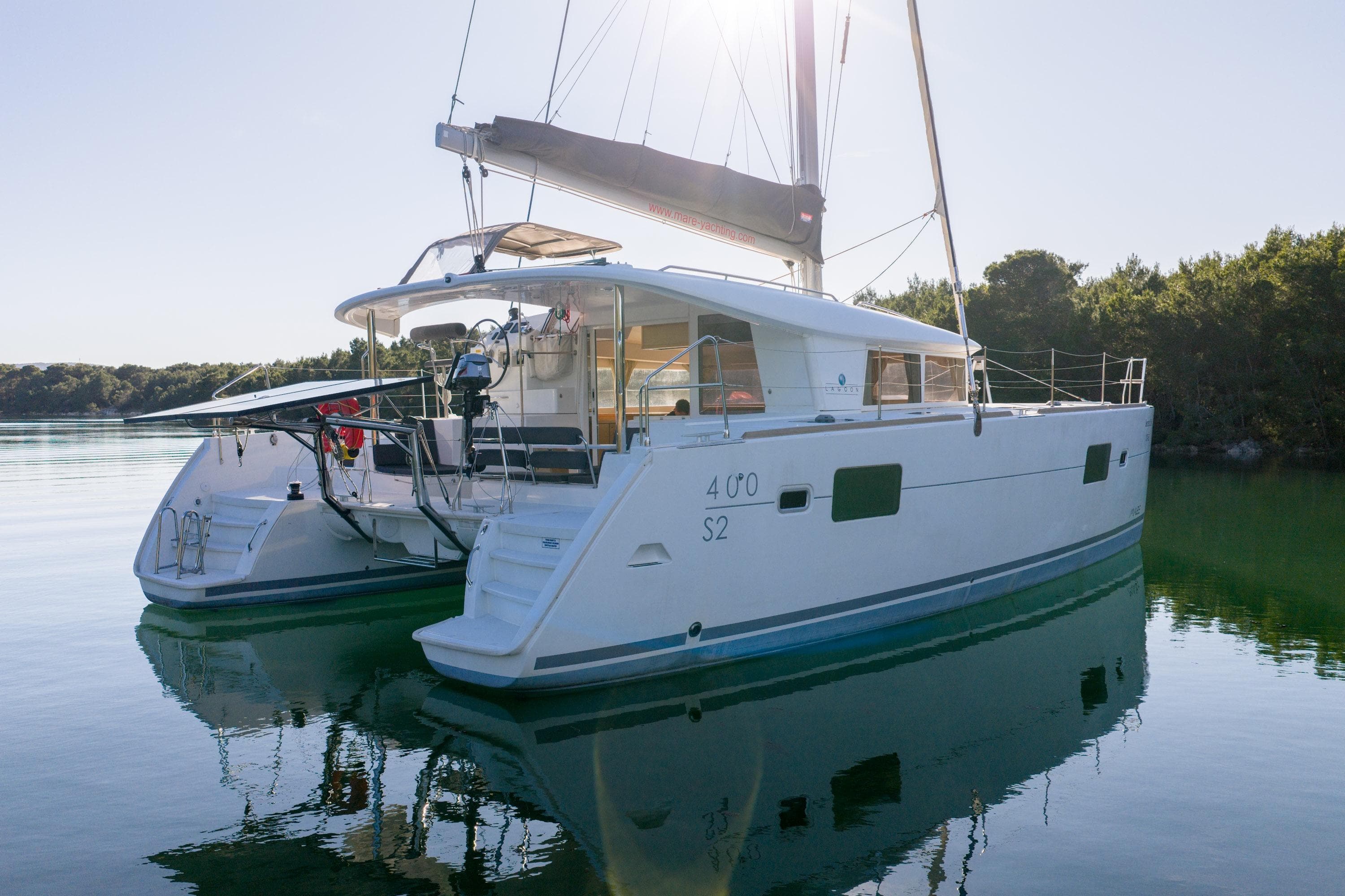 2015 Lagoon 400 S2 catamaran anchored in serene waters, surrounded by lush greenery.