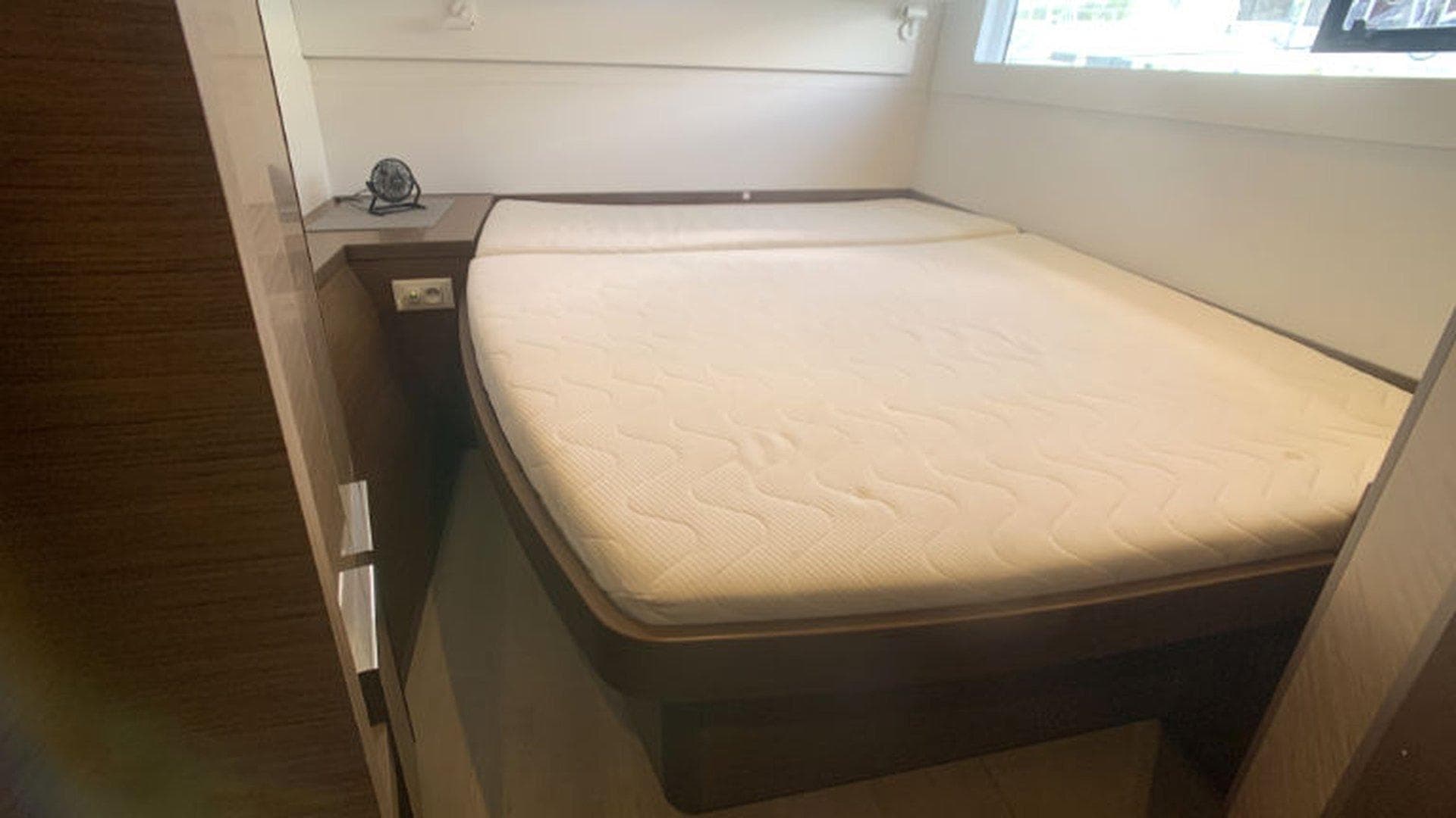 Cabin interior of 2019 Lagoon 40 catamaran with a comfortable bed and wooden accents.