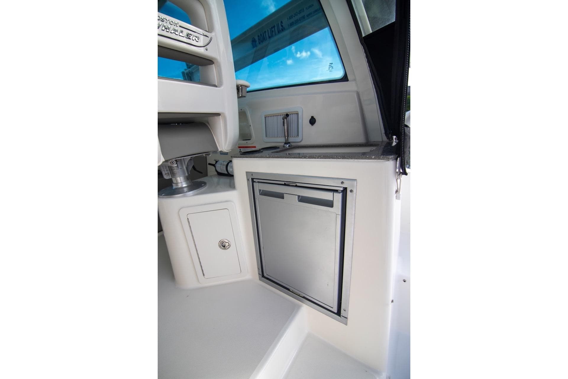 2014 Boston Whaler 315 Conquest interior with compact refrigerator and storage.