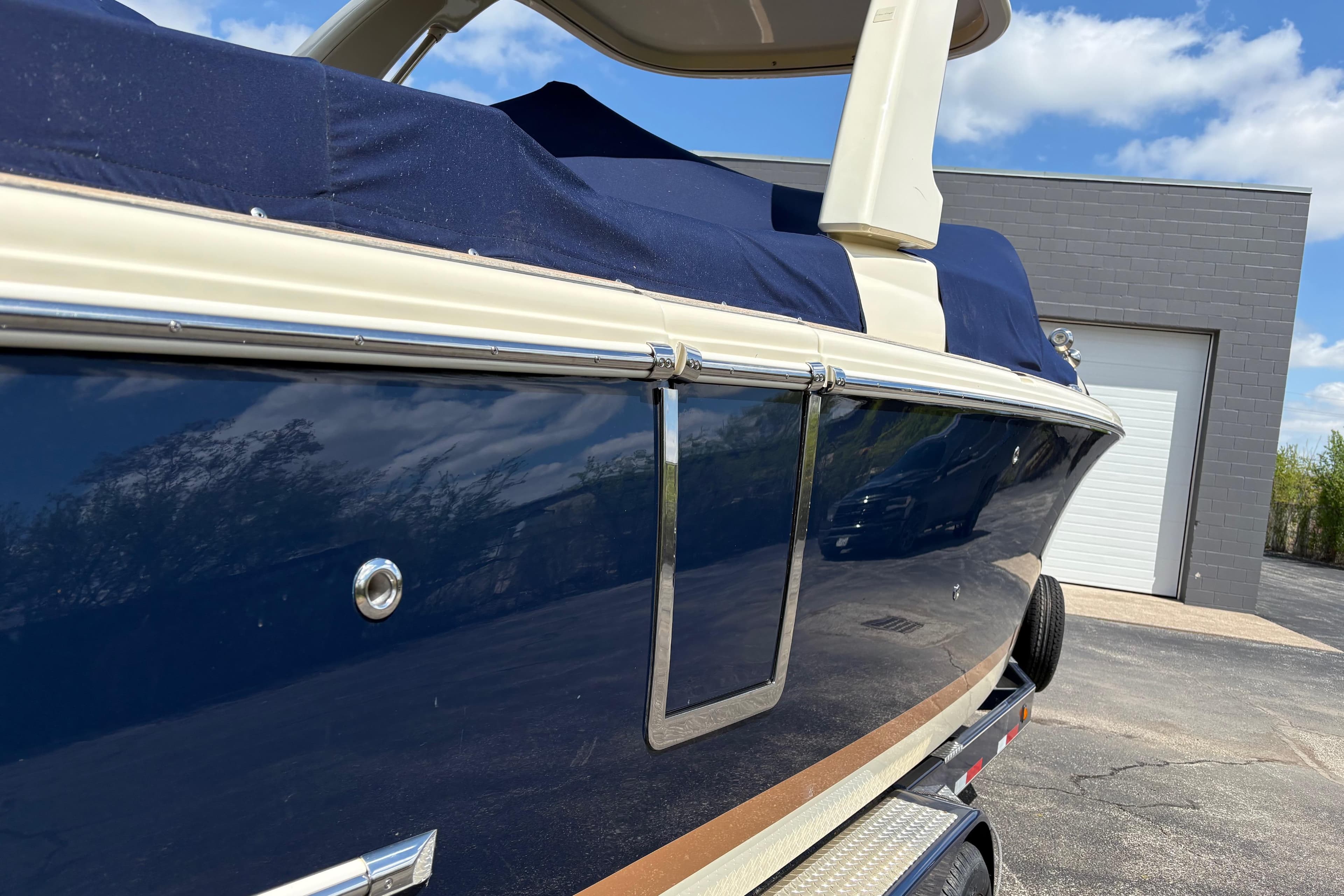 2022 Chris-Craft Launch 28 GT boat with blue cover, parked outdoors.