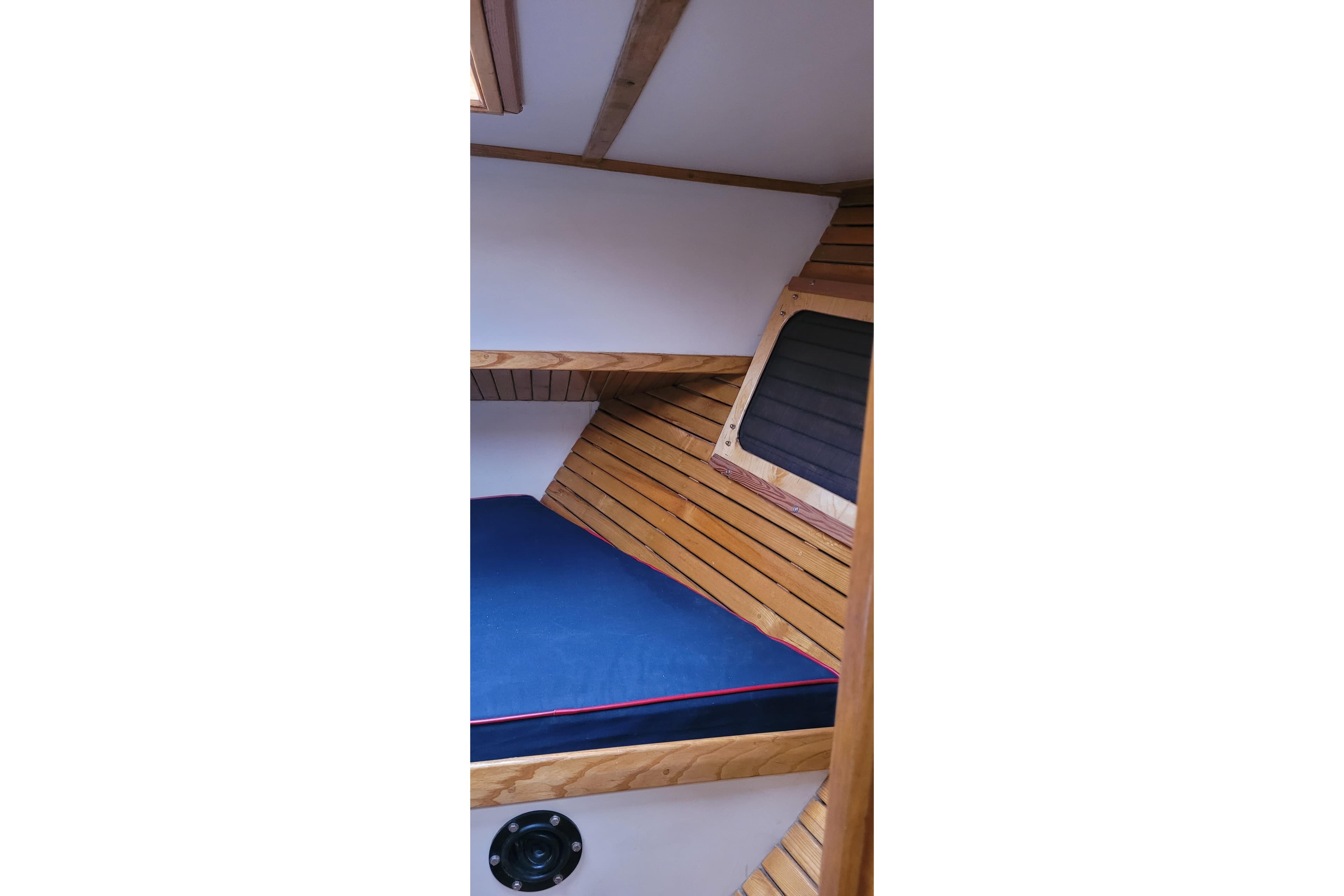 Interior cabin of 1983 Corbin 39 sailboat with wooden paneling and blue cushion.