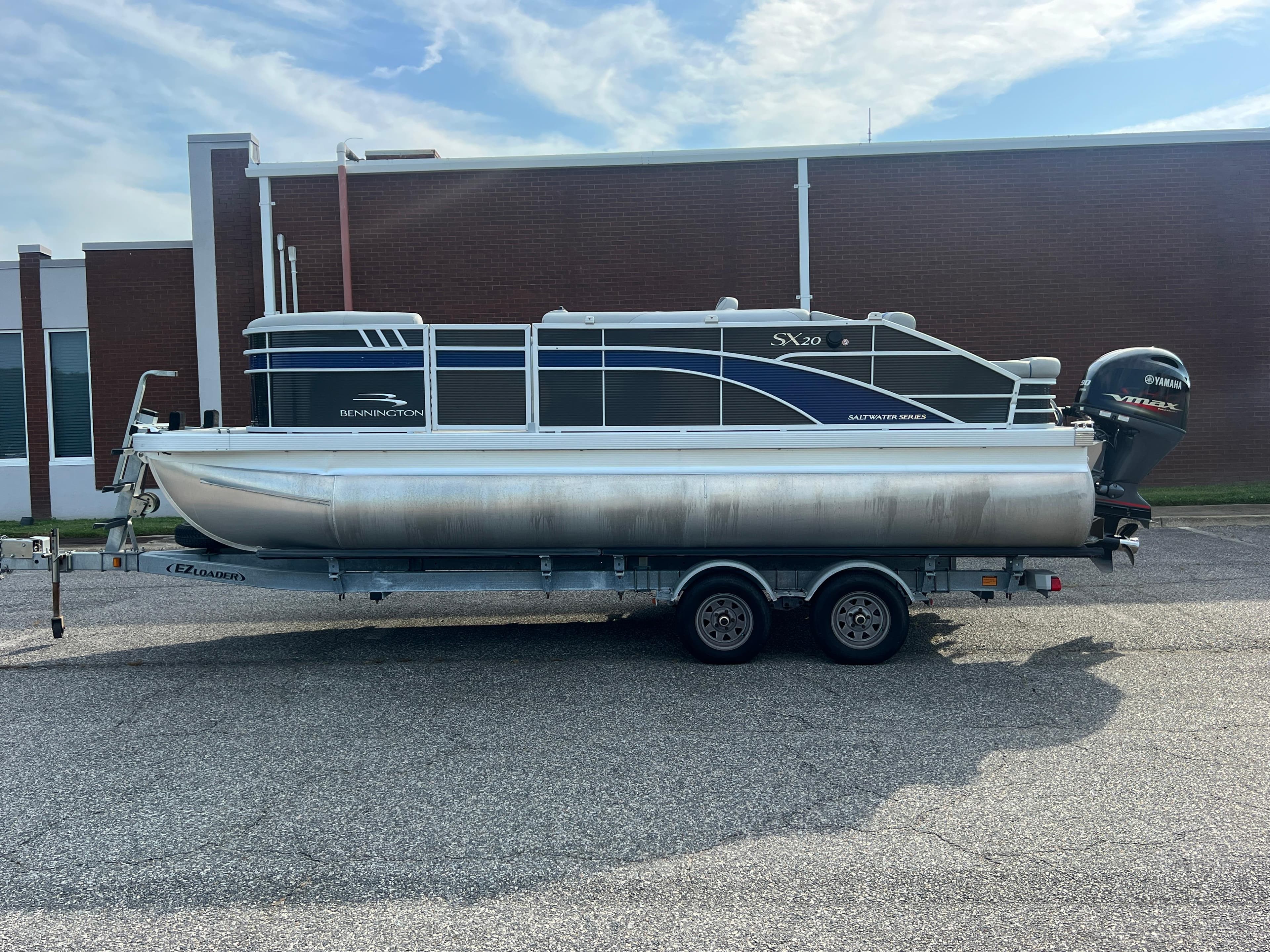 2022 Bennington SX 20 Swingback pontoon boat on trailer, parked outdoors.