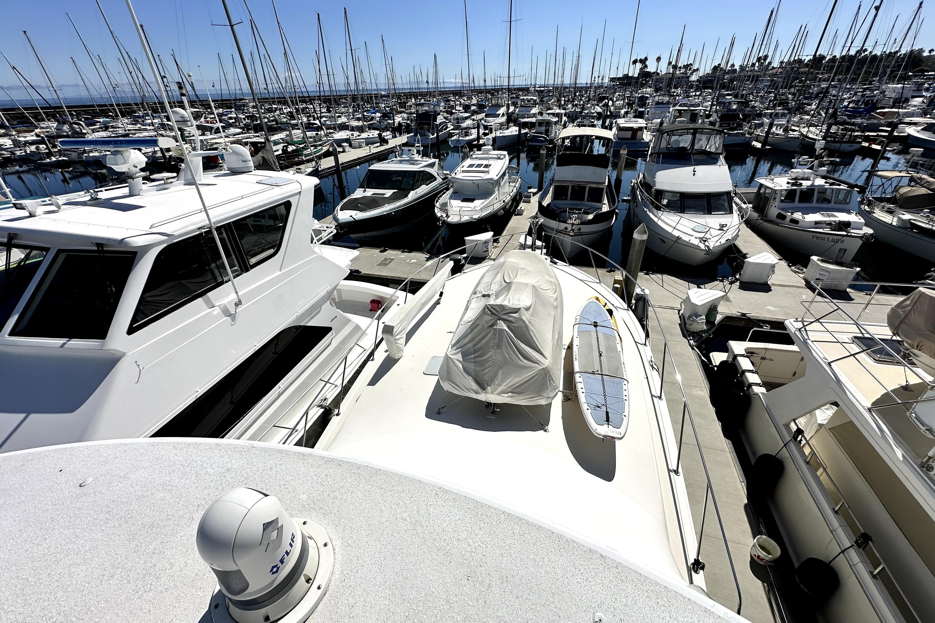 Marina with numerous boats, including a 2003 Viking 61 Convertible yacht, docked under clear skies.