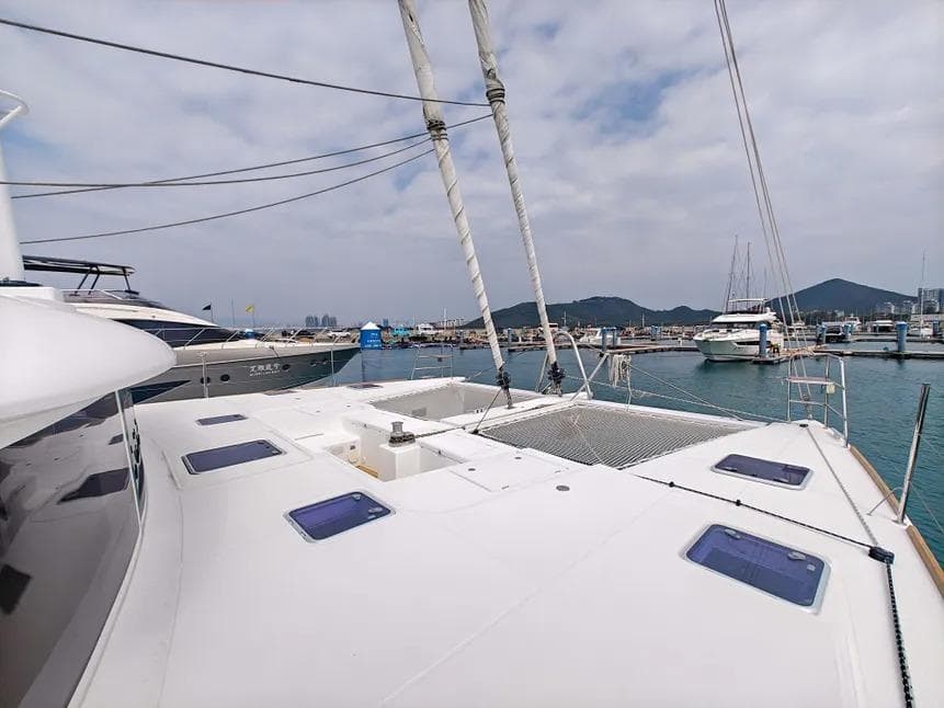 2012 Lagoon 560 catamaran docked at a marina with scenic mountain views.