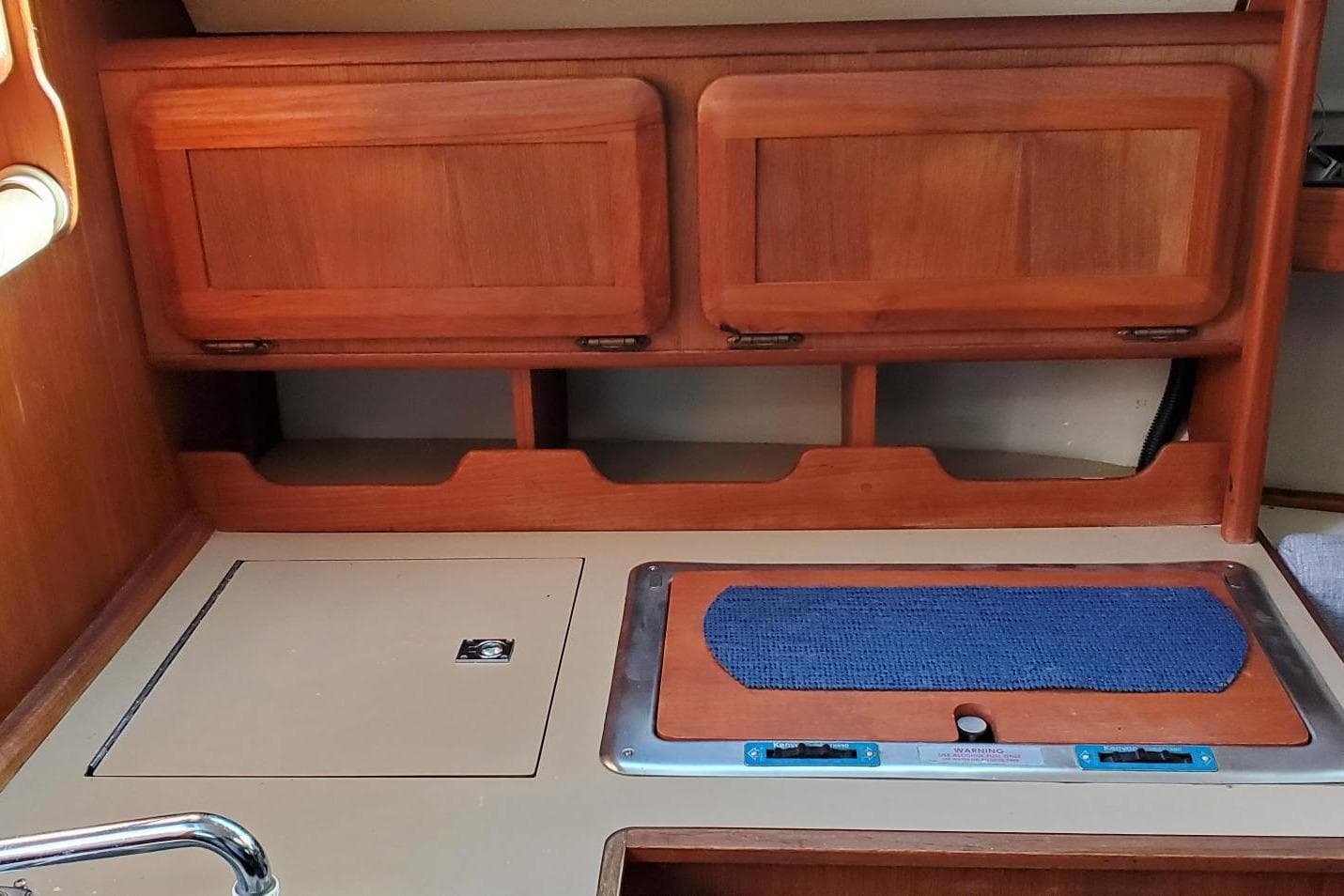 Interior of a 1990 Hunter 28 sailboat featuring wooden cabinetry and a compact kitchen area.