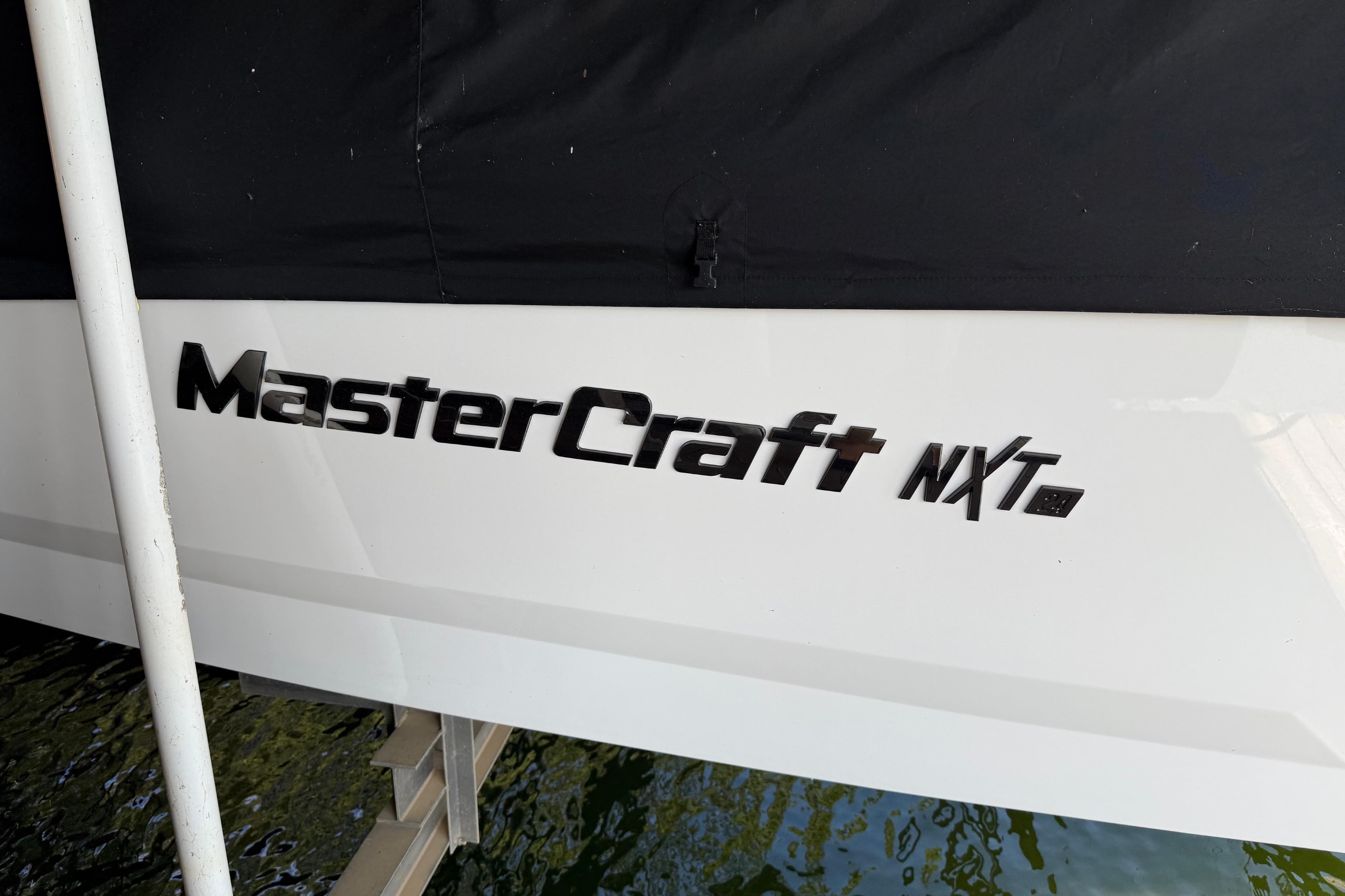 2022 MasterCraft NXT24 boat logo on white hull, partially covered.