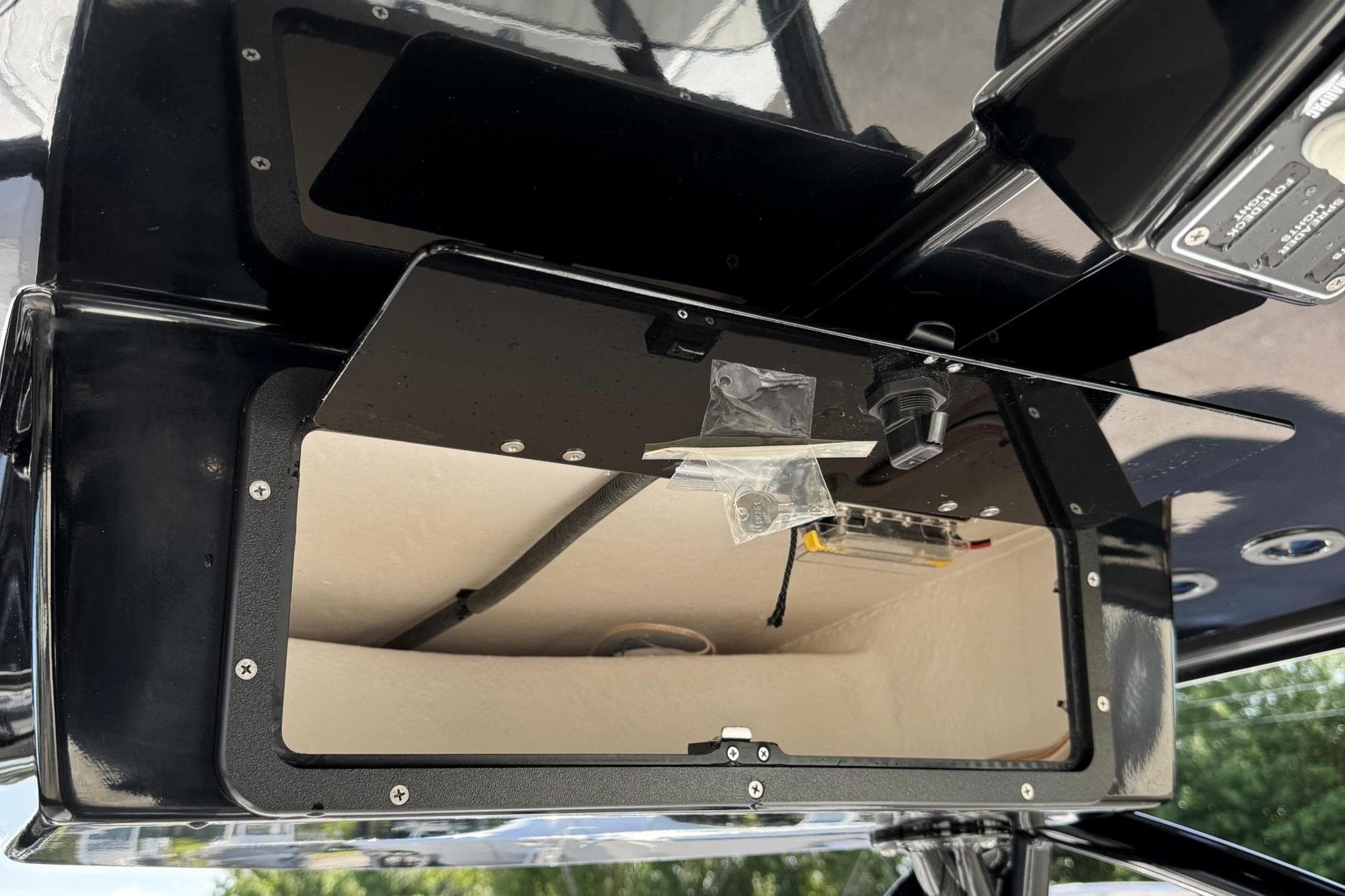 Open storage compartment on 2026 BlackJack 256 Coastal boat, featuring sleek black design.
