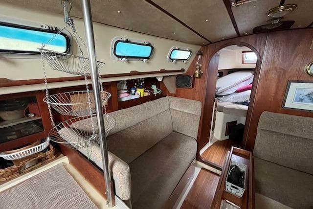 Interior of a 1983 CS 33 sailboat with cozy seating and wooden accents.