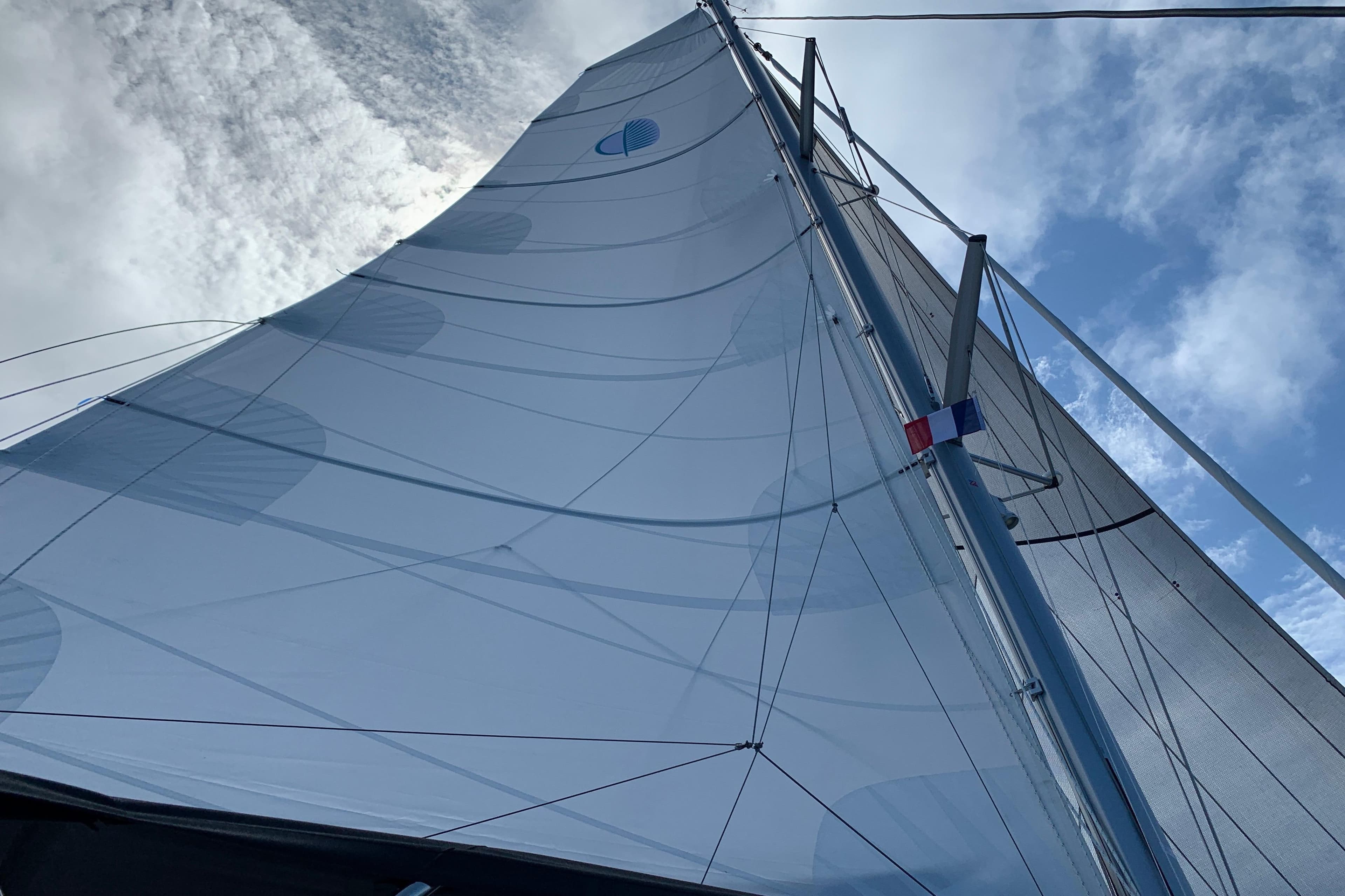Sailing yacht Lagoon 46, 2021 model, with sails unfurled against a cloudy sky.