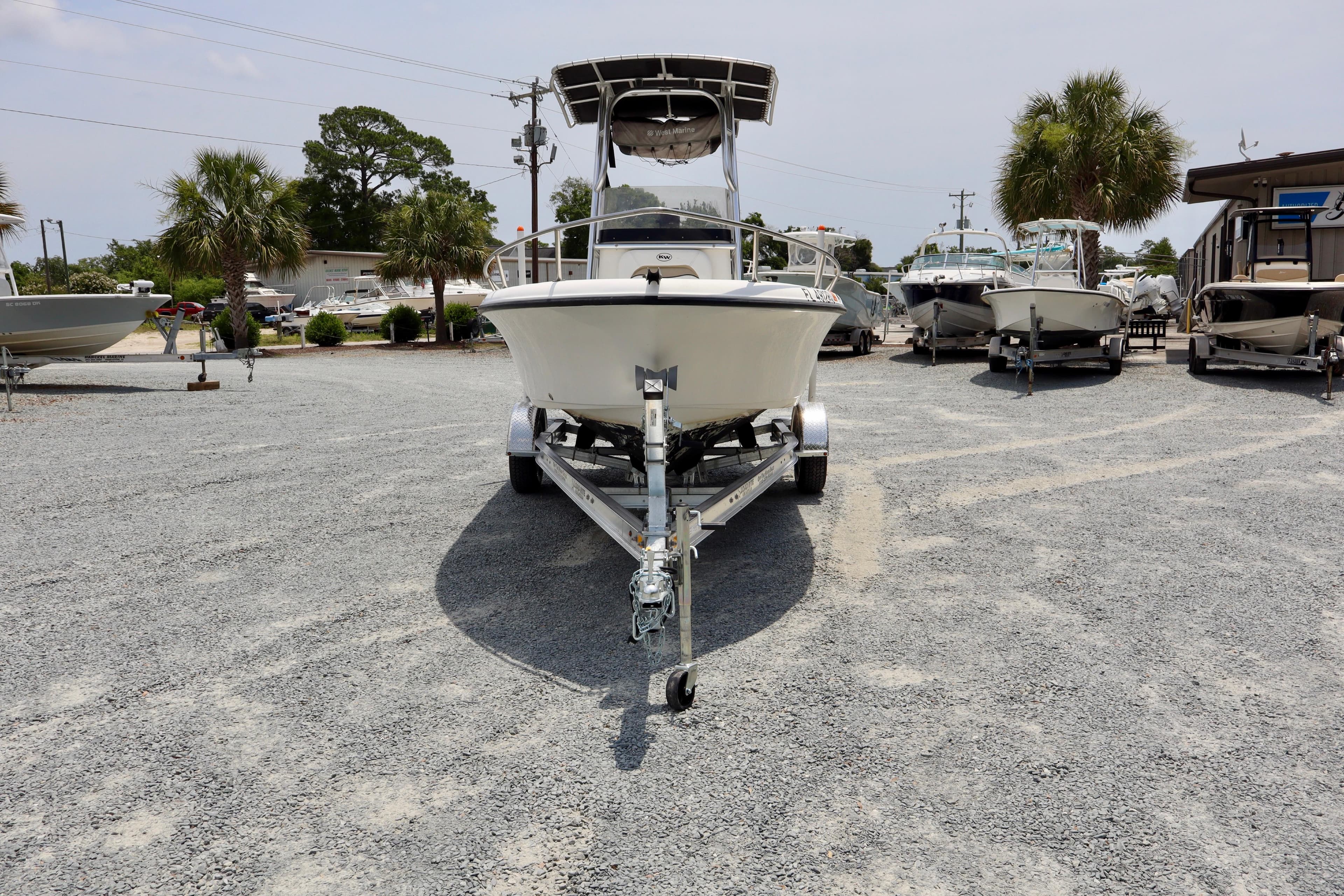 2010 Key West 186 Sportsman boat on trailer in a gravel lot with palm trees.