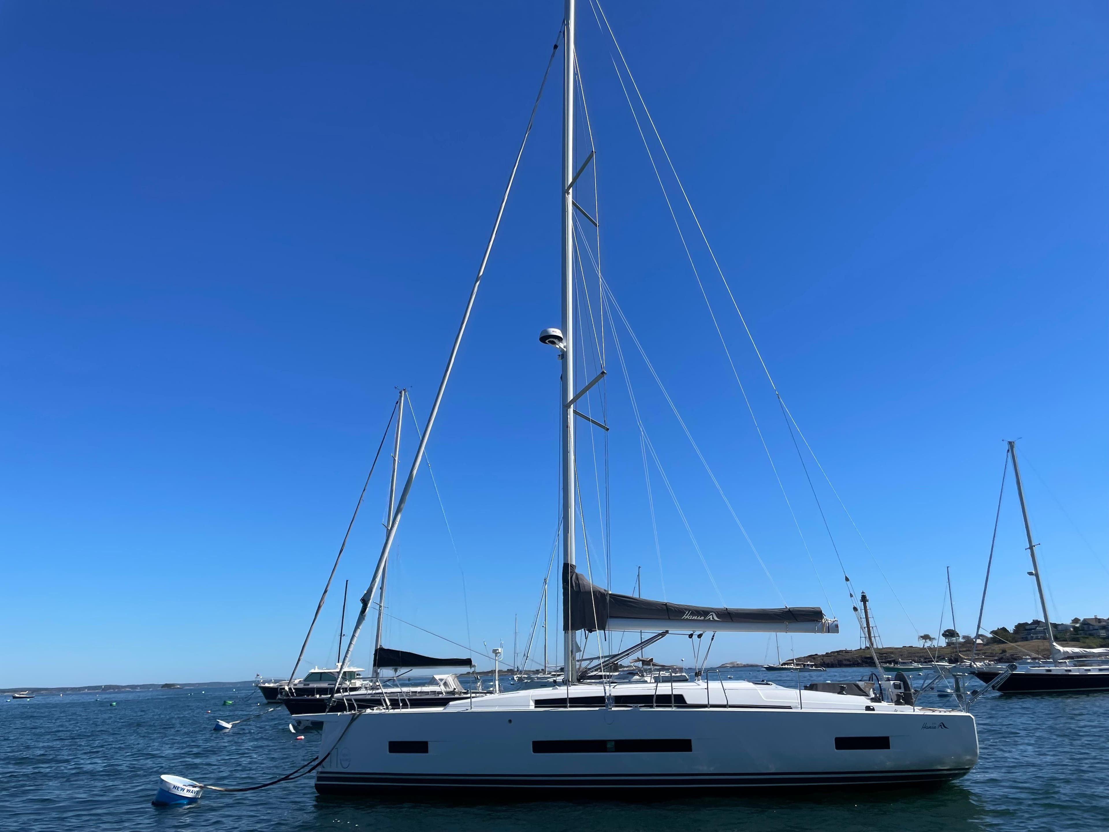 2024 Hanse 410 sailboat on calm water under clear blue sky.